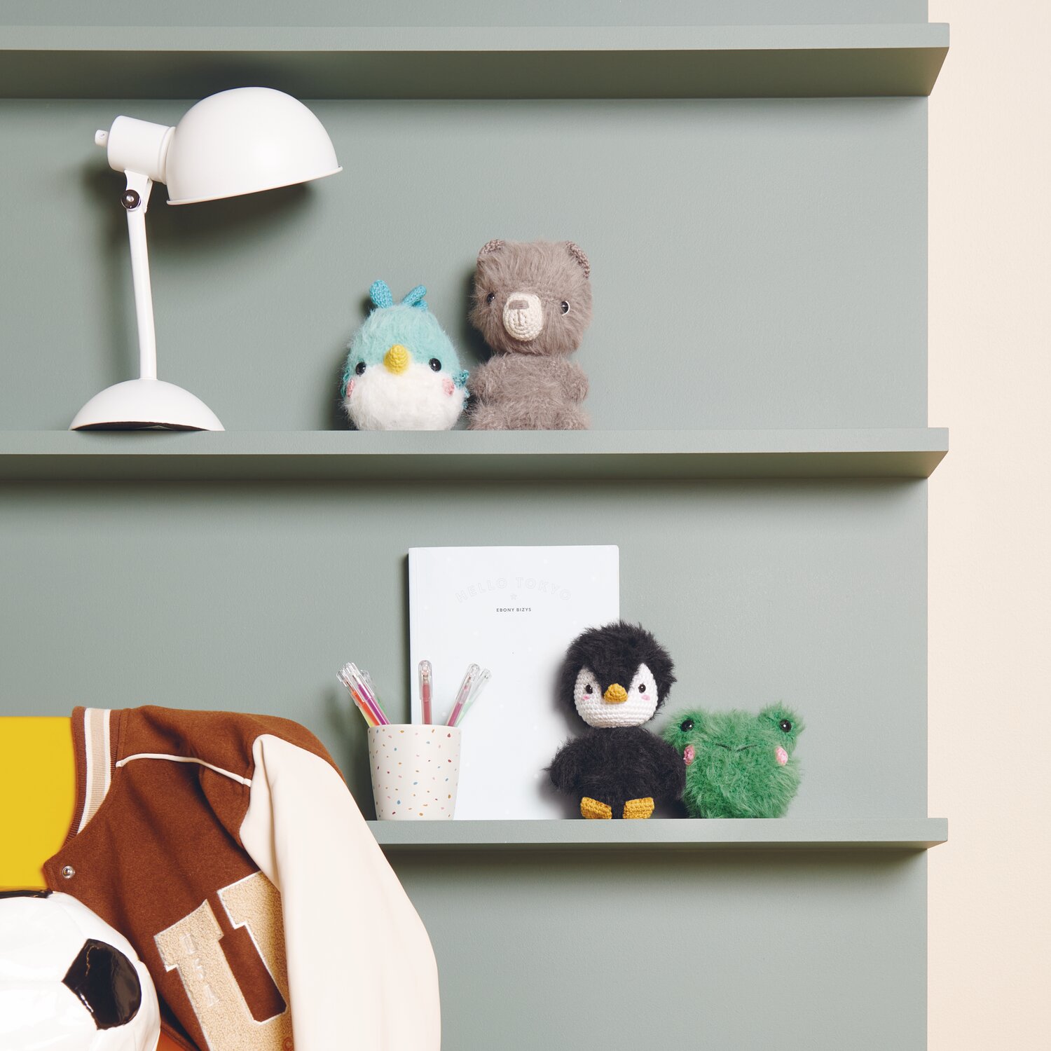 Ricorumi Furry Animals auf grünem Regal mit Lampe und Schreibutensilien, dekoriert mit Plüschtieren.