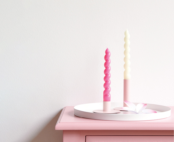 Zwei Kerzenständer sind dekorativ auf einem rosa Regal angerichtet. 