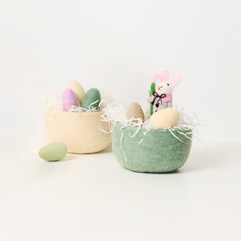 Zwei Osterkörbe aus Filz sind mit Filzeiern und einer Hasenfigur aus Filz gefüllt.