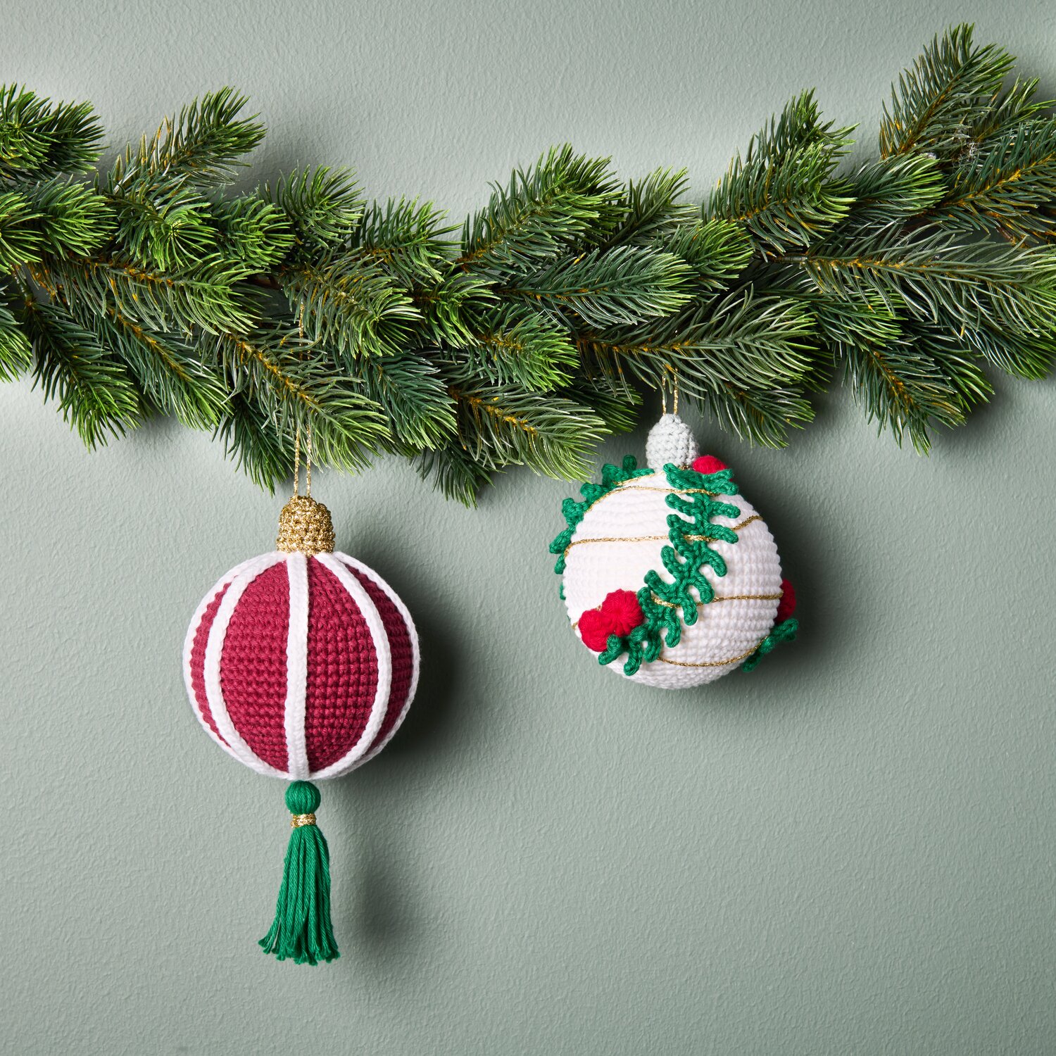 Ricorumi Häkelset Christbaumkugeln Gold: Zwei gehäkelte Kugeln in Rot und Weiß an Tannenzweigen.