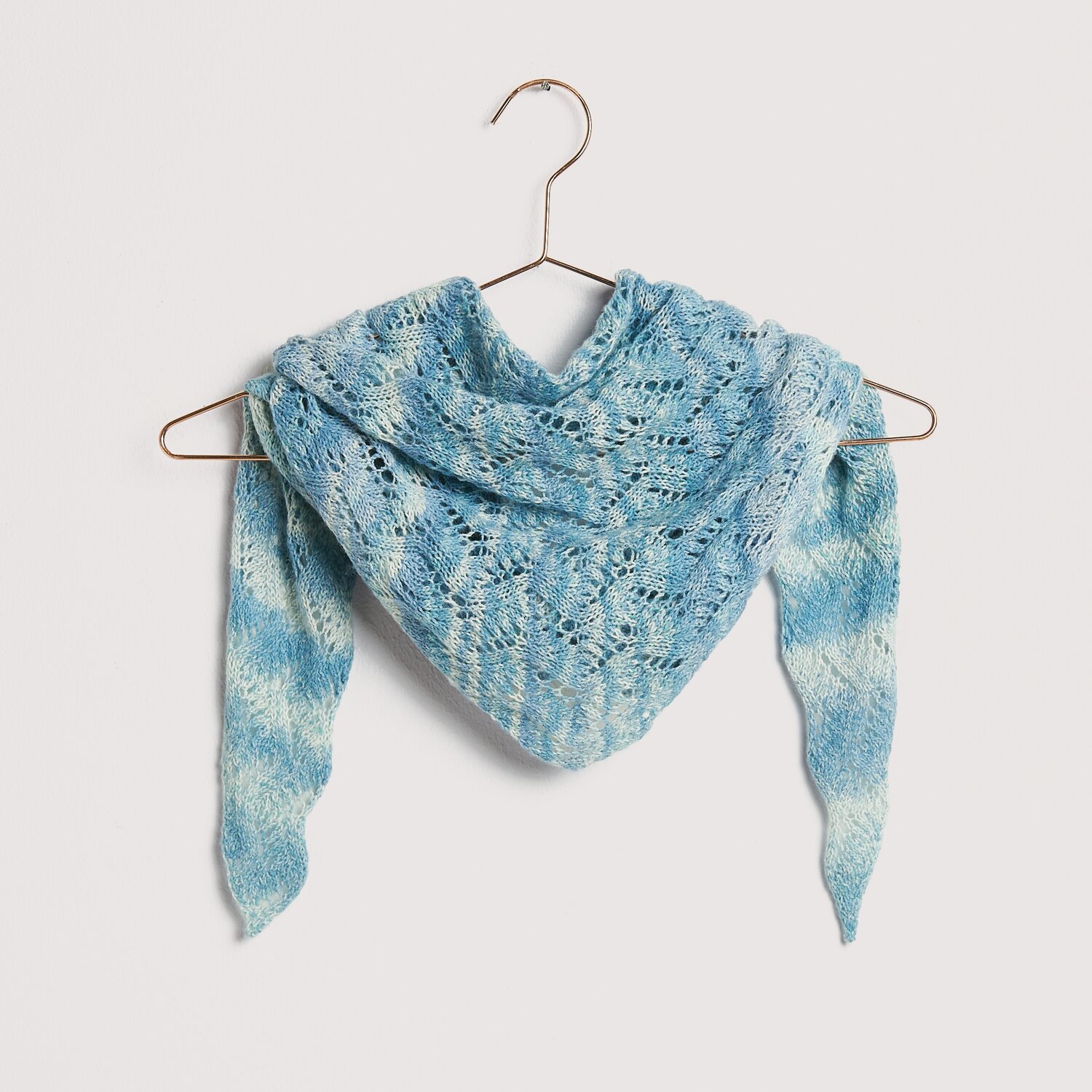 Strickset Dreieckstuch Modell 25 in Blau auf einem Kleiderbügel. Aus Die Neue Masche No. 12.