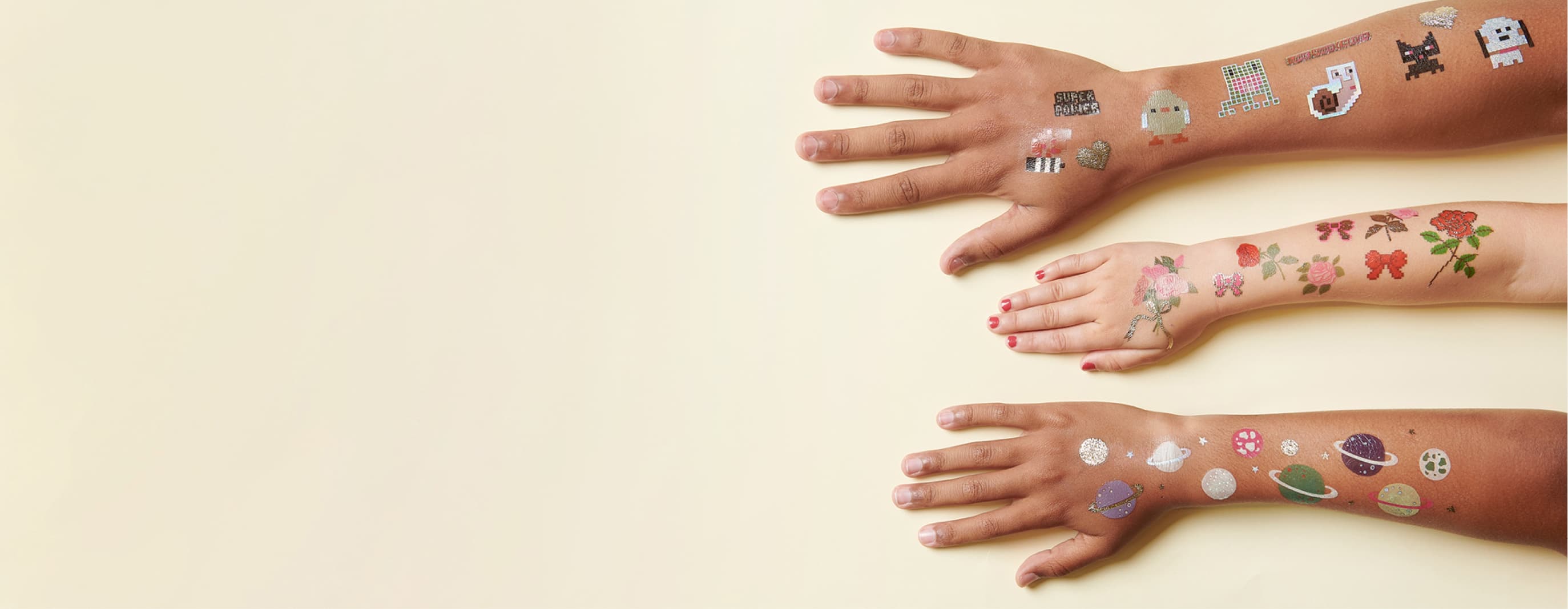 Arme sind mit temporären Tattoos beklebt in verschiedenen Designs mit Rosen, Tier und Planet-Motiven.