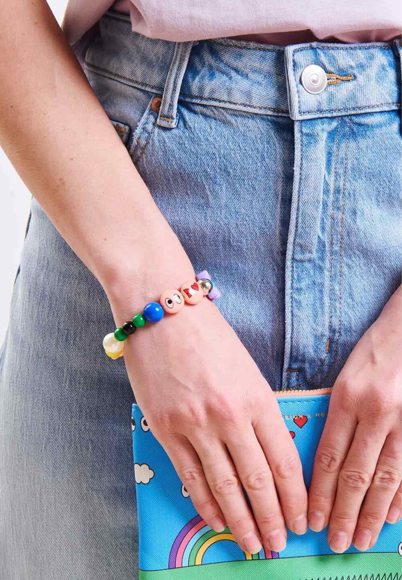 Ein buntes Perlenarmband wird am Handgelenk getragen.