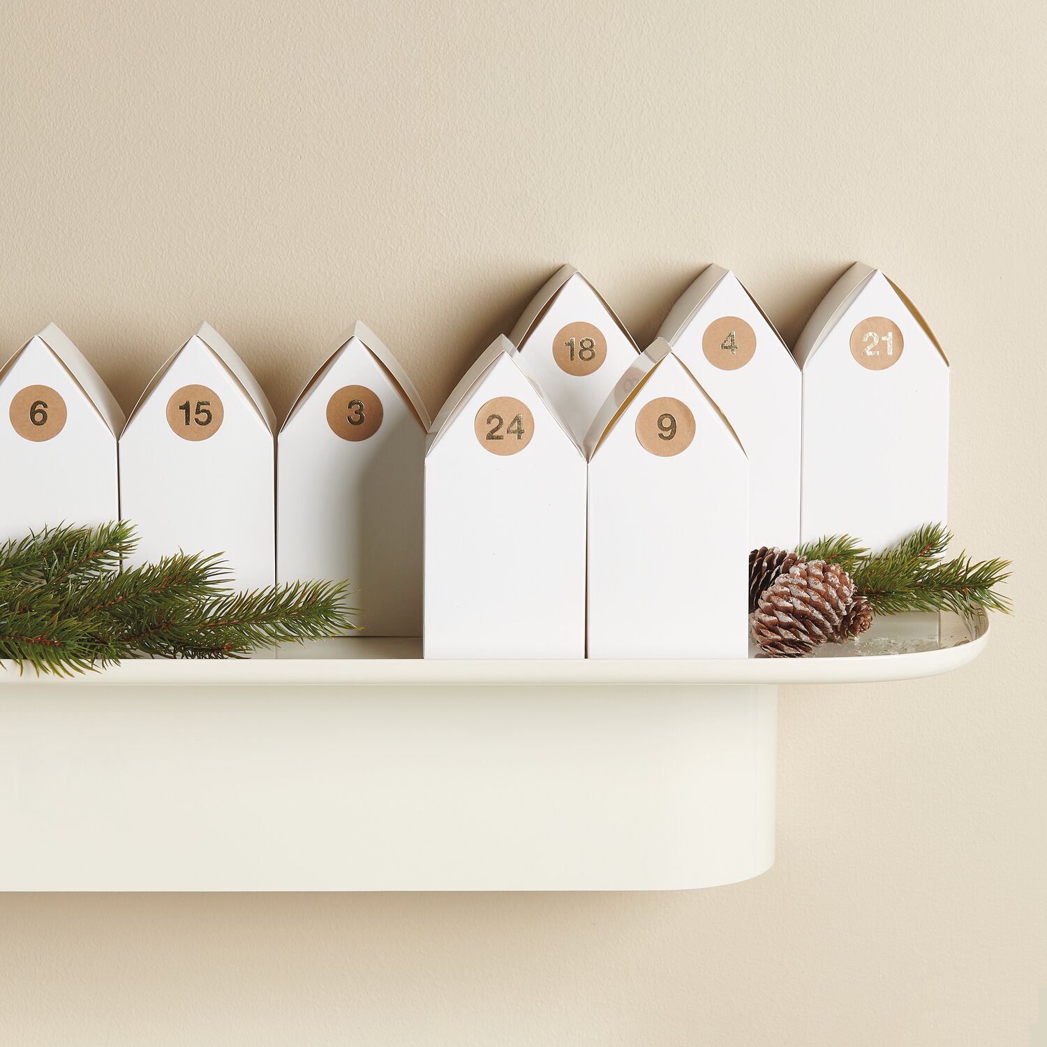 Paper Poetry Papphäuser vorgestanzt: Adventskalender aus weißem Karton, dekoriert mit Zahlen und Tannenzweigen, ideal für kreative Weihnachtsdekoration.