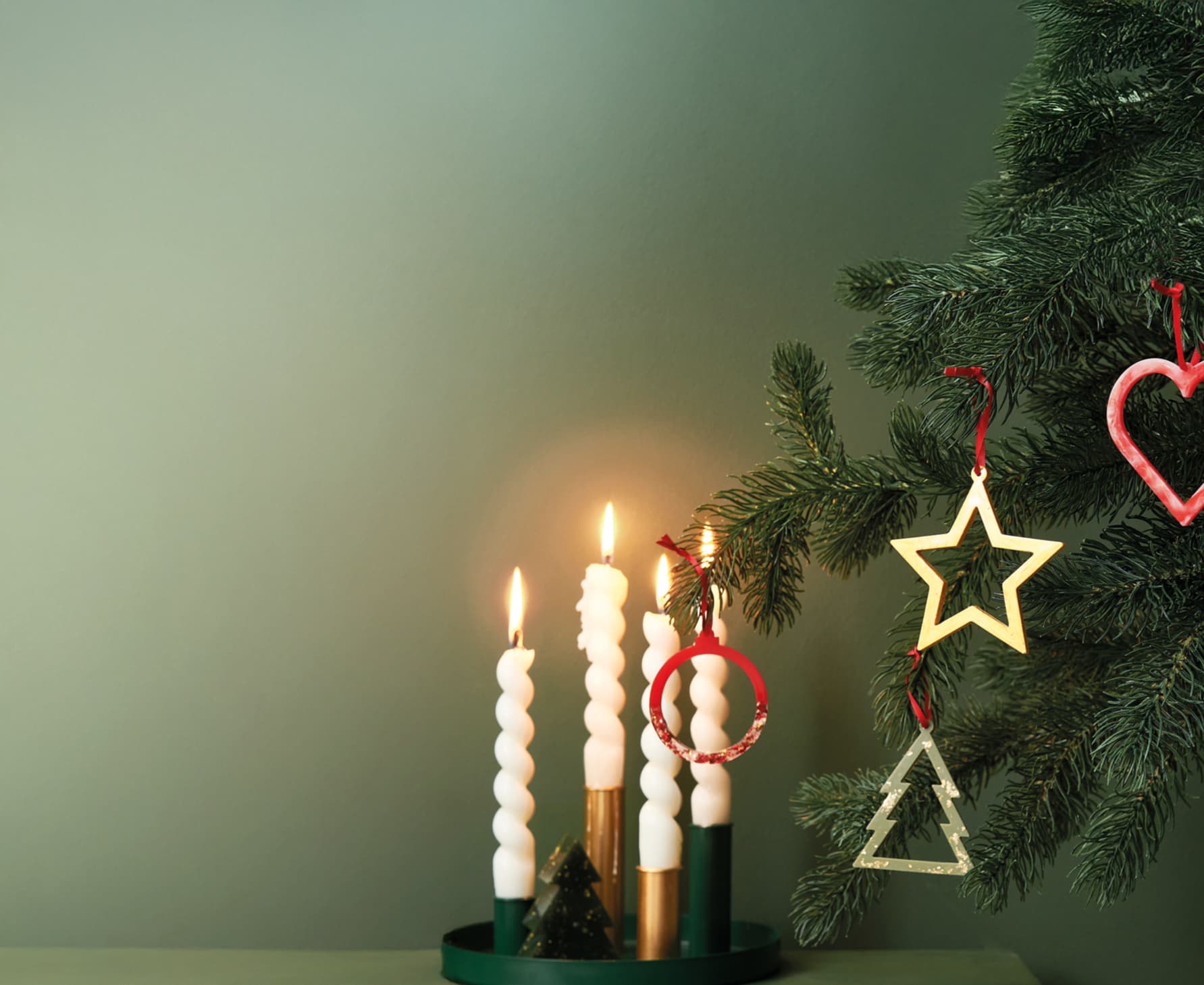 Weihnachtsanhänger aus Resin hängen weihnachtlich dekoriert an einem Tannenzweig. 