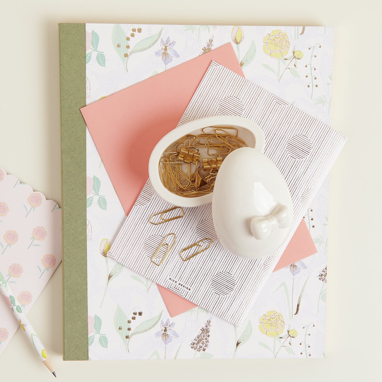 Keramik Dose Ei mit Schleife, weiß, gefüllt mit Büroklammern, auf Notizbüchern arrangiert.