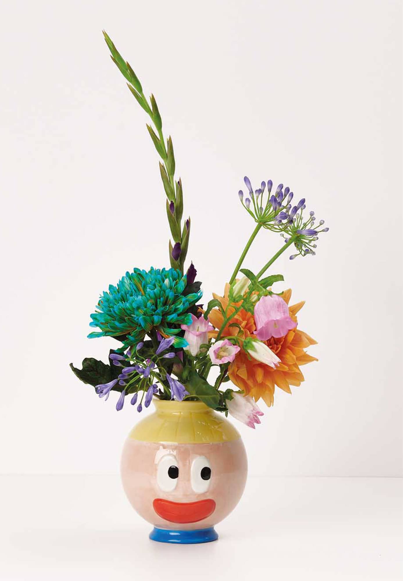 Eine Vase mit Gesicht ist mit Blumen bestückt.