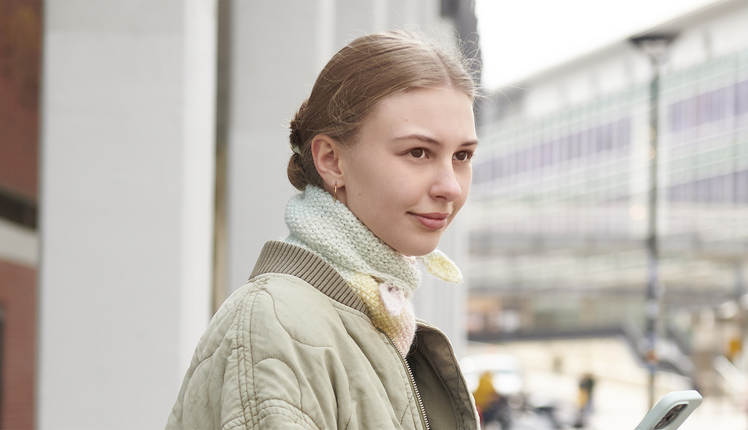 Strickanleitung Mini Dreieckstuch mit Pastellverlauf Strickanleitung Mini Dreieckstuch mit Pastellverlauf: Frau trägt ein pastellfarbenes Tuch in urbaner Umgebung.
