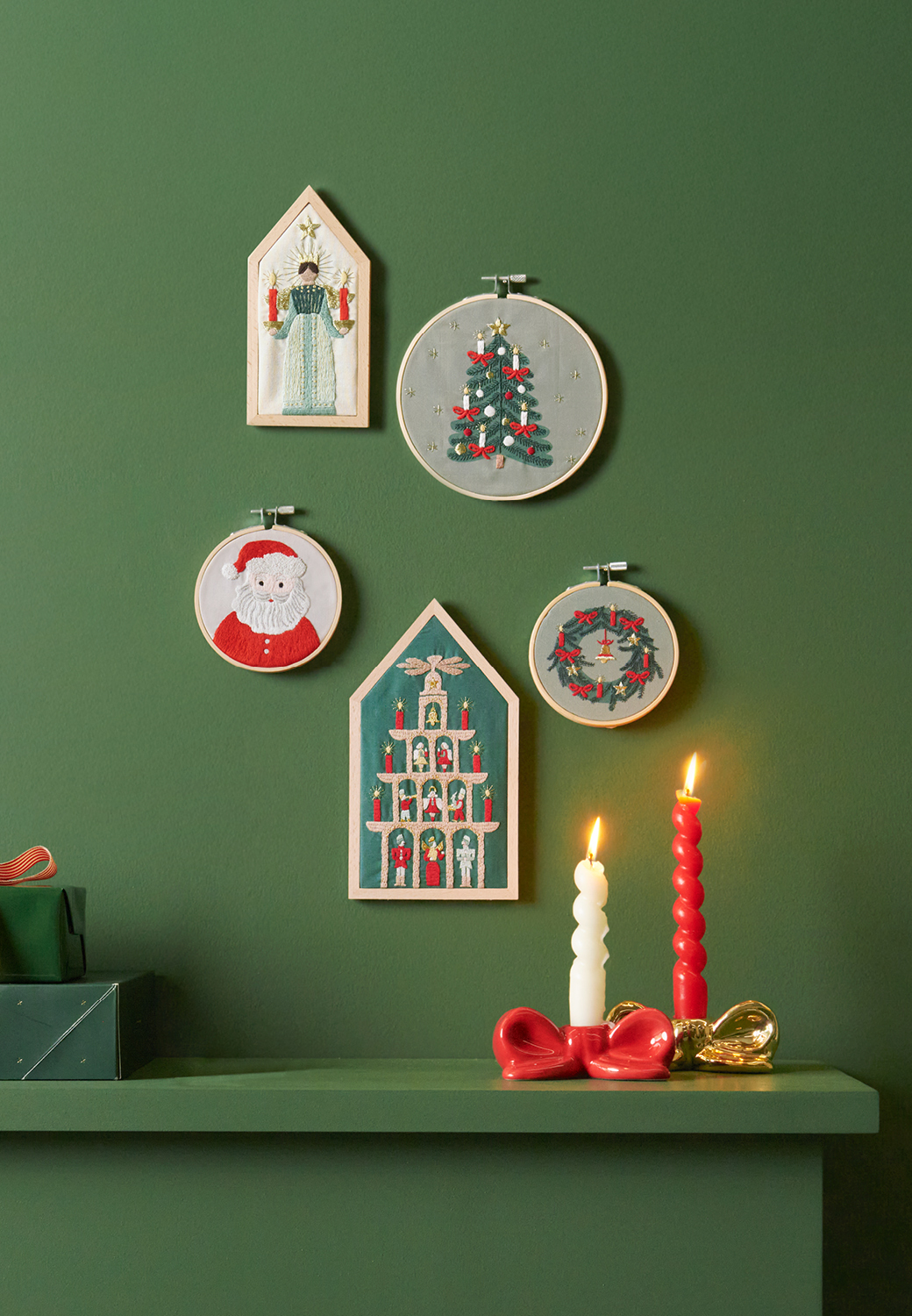 Stickbilder in verschiedenen Formaten und Größen mit weihnachtlichen Motiven hängen an grüner Wand