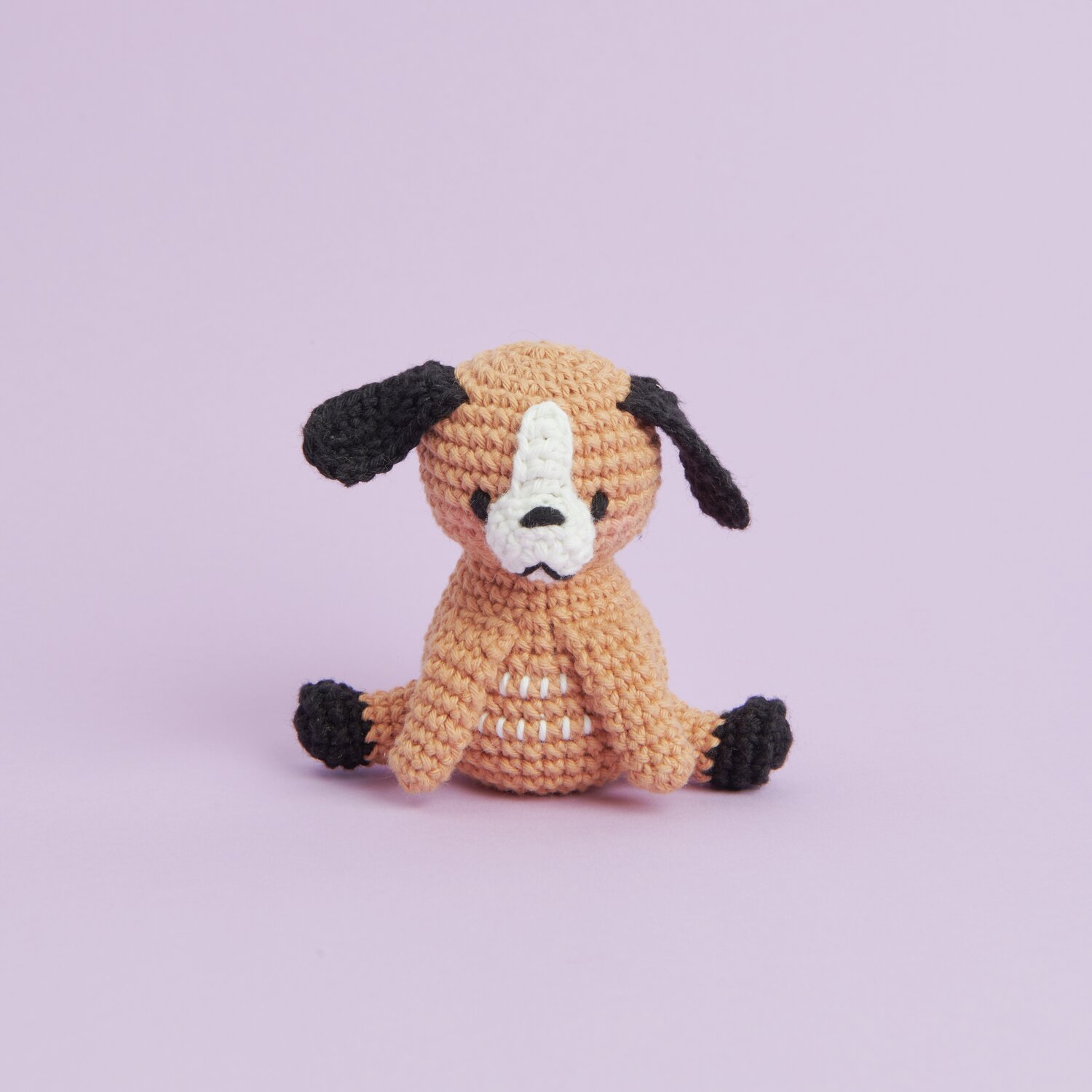 Ricorumi Mini Easy Häkelset - Hund: Niedlicher gehäkelter Hund in Braun und Schwarz auf lila Hintergrund.