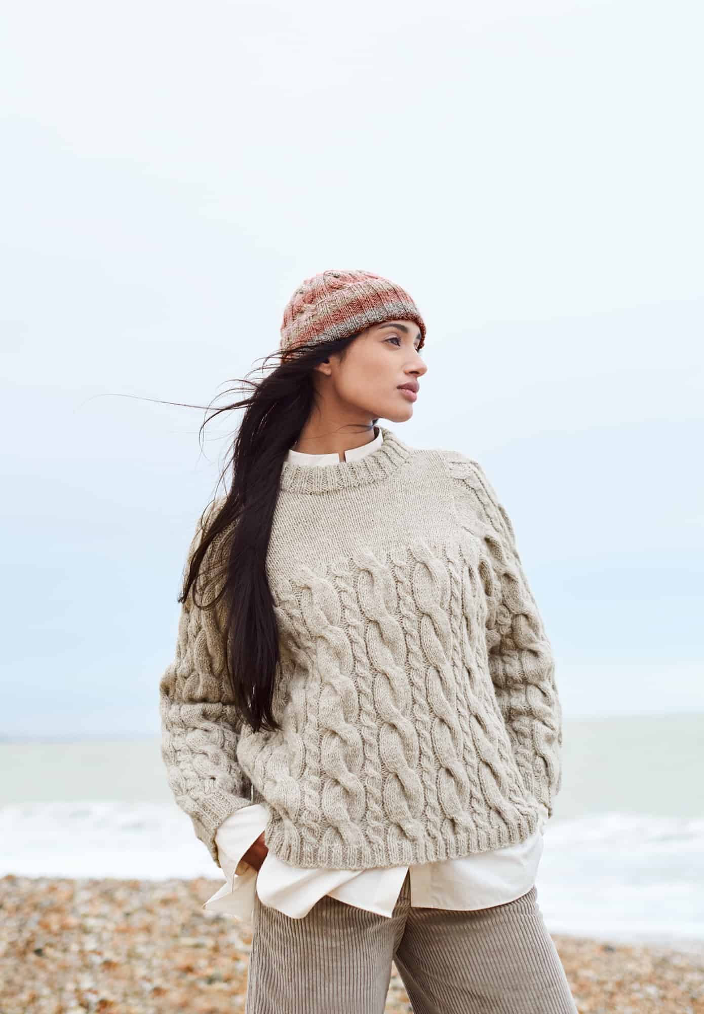 Frau trägt gestrickten Pullover mit Zopfmuster in Natur: Modell 22 aus Lovewool No. 21