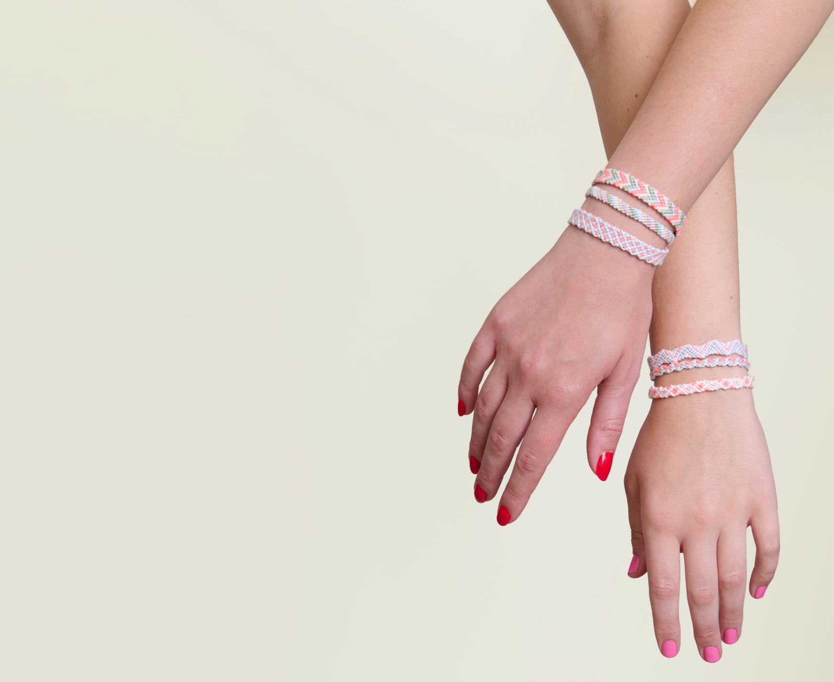 Zwei Hände halten sich und tragen geknüpfte Freundschaftsarmbänder am Handgelenk. 