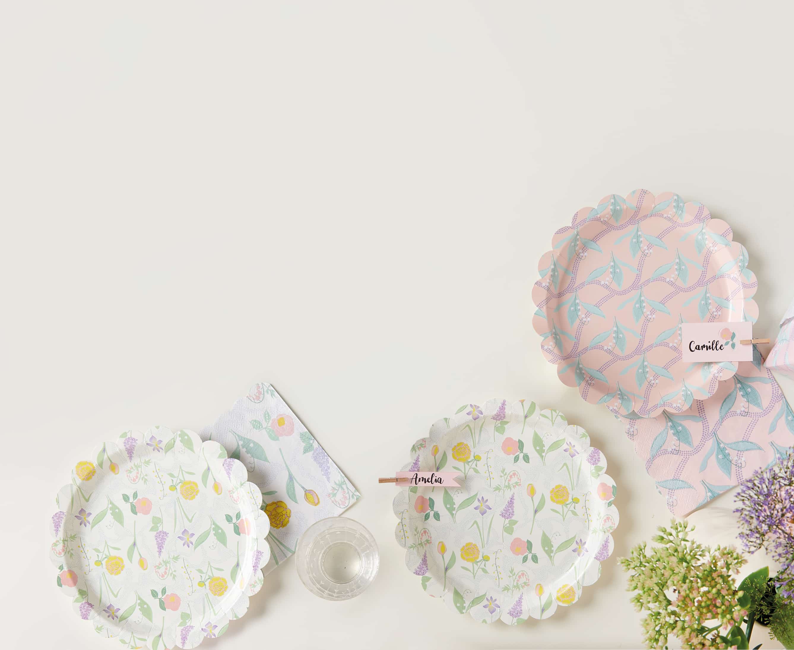 Pappteller und Servietten mit Blumenmustern sind auf einem Tisch dekoriert. 