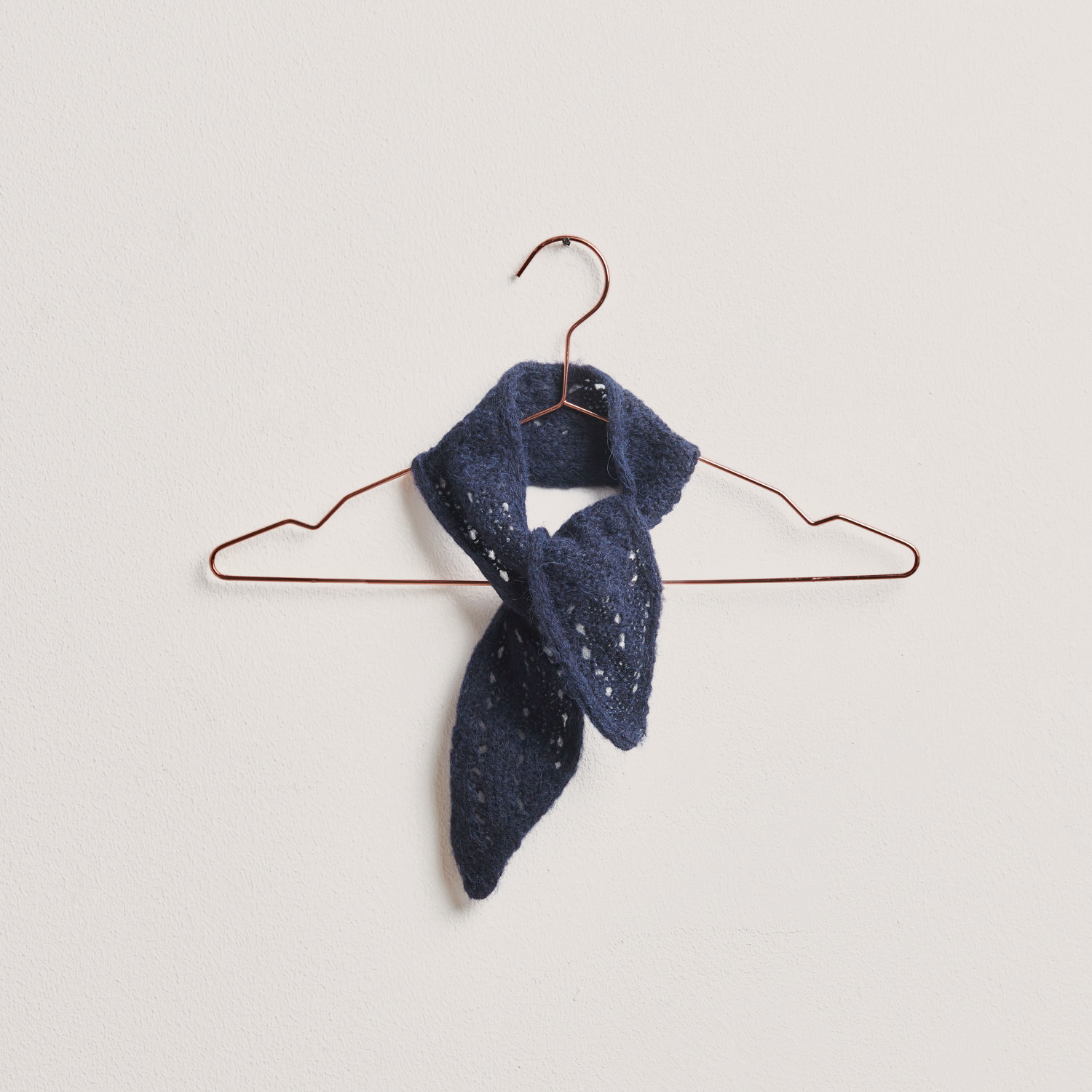 Strickset Mini-Tuch Modell 31: Elegantes, marineblaues Tuch aus Alpaka-Seide, hängend an einem Kupferbügel. Ideal für den Winter.
