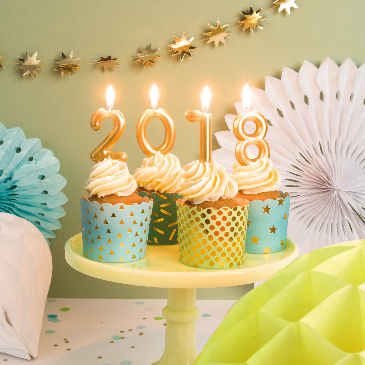 Zahlenkerze Gold von Rico Design auf Cupcakes mit Ziffern 2018, dekoriert mit Partygirlanden und Papierrosetten für eine festliche Tischdeko