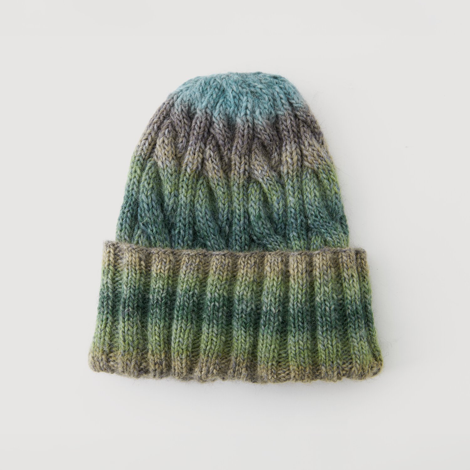 Strickmütze in Blau- und Grüntönen, Modell Legeware. Die Mütze zeigt ein Zopfmuster und ist ideal für kalte Tage. Perfekt für stilvolle Wintermode.