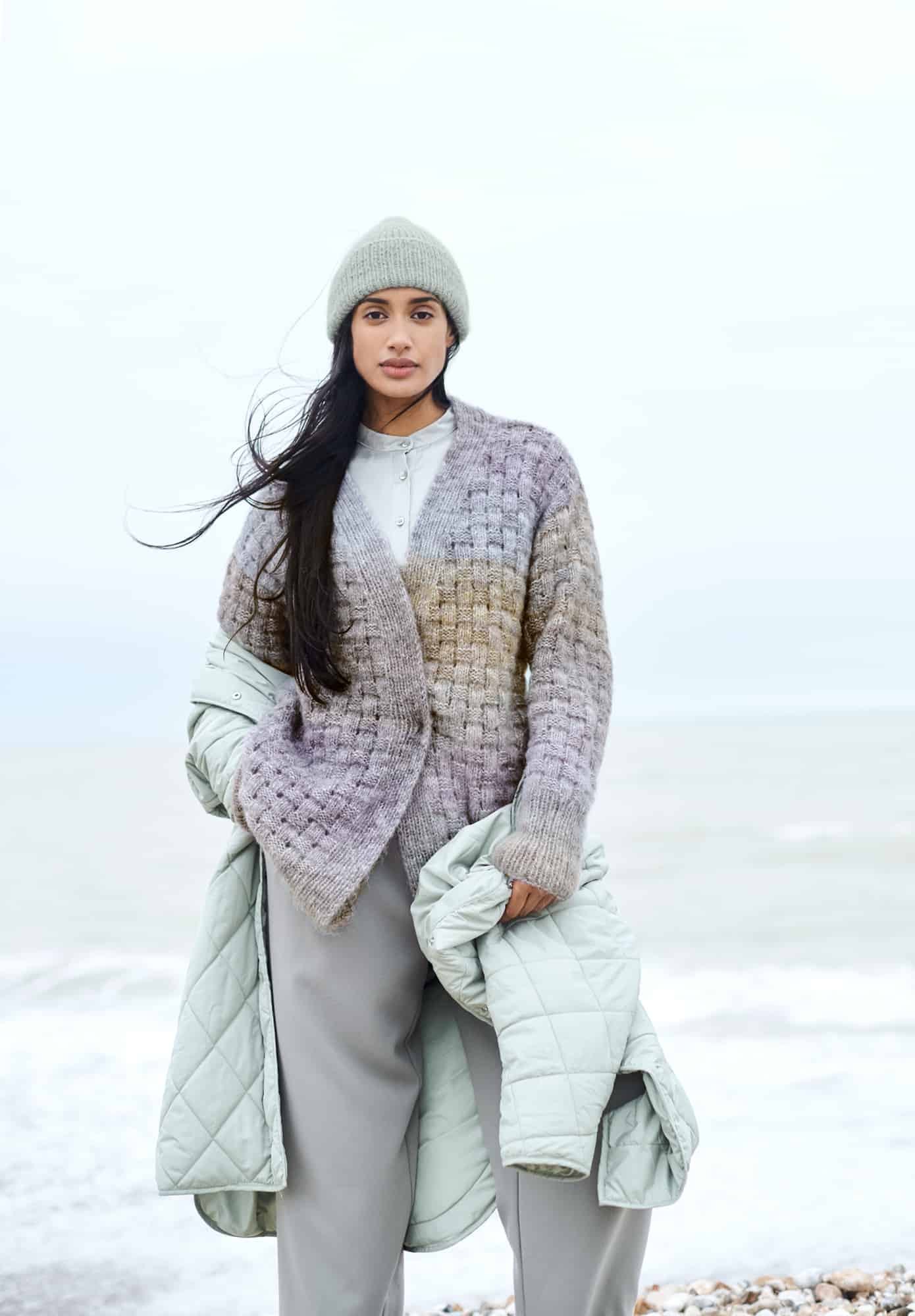 Frau trägt gestrickte Jacke mit Flechtmuster in Pastellfarben: Modell 21 aus Lovewool No. 21