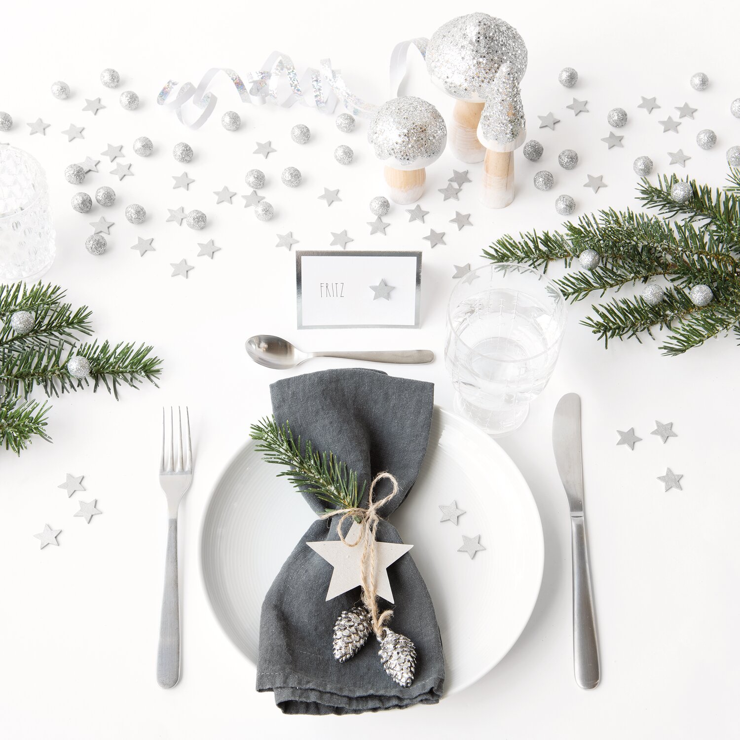 Holzstreu Stern 20x19mm 48 Stück dekoriert einen festlichen Tisch mit Tannenzweigen und silbernen Akzenten. Ideal für elegante Anlässe.