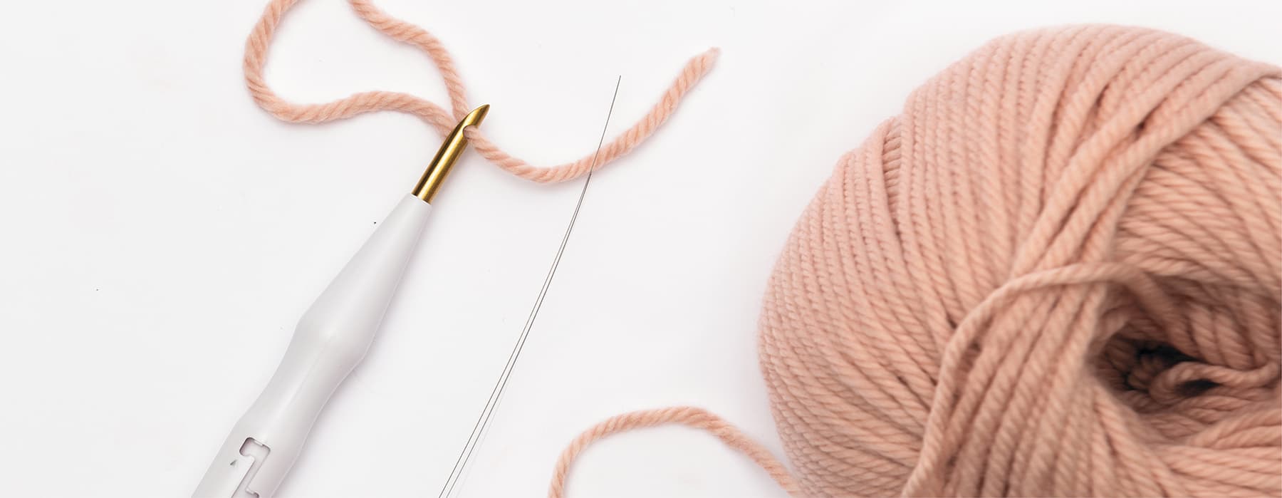 Punch Needle und rosa Wollknäuel auf weißem Hintergrund