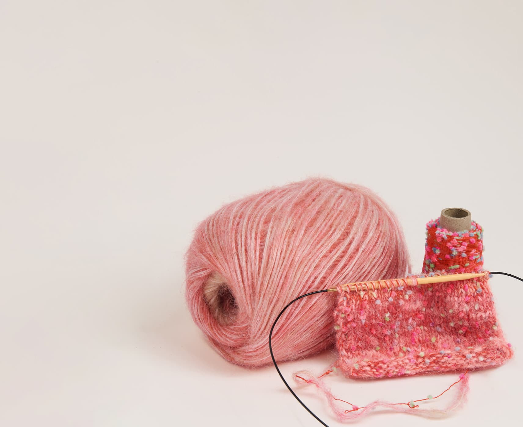 Effektgarn „Creative Make It Flöckchen“ als Garnknäuel mit angestrickter Maschenprobe auf hellem Hintergrund.