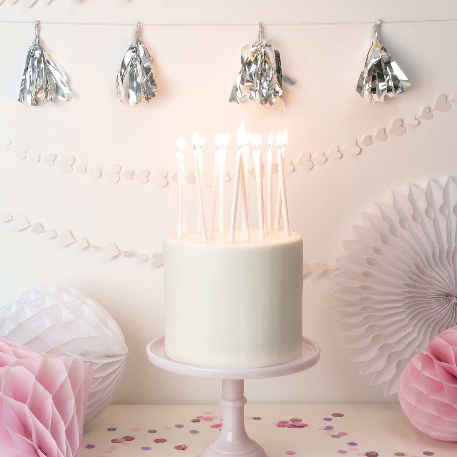 Kerzen lang 12cm für Geburtstagskuchen, Rico Design, glitzernde Stabkerzen in Weiß, 16 Stück, auf Torte in pastellfarbener Partydekoration stehend