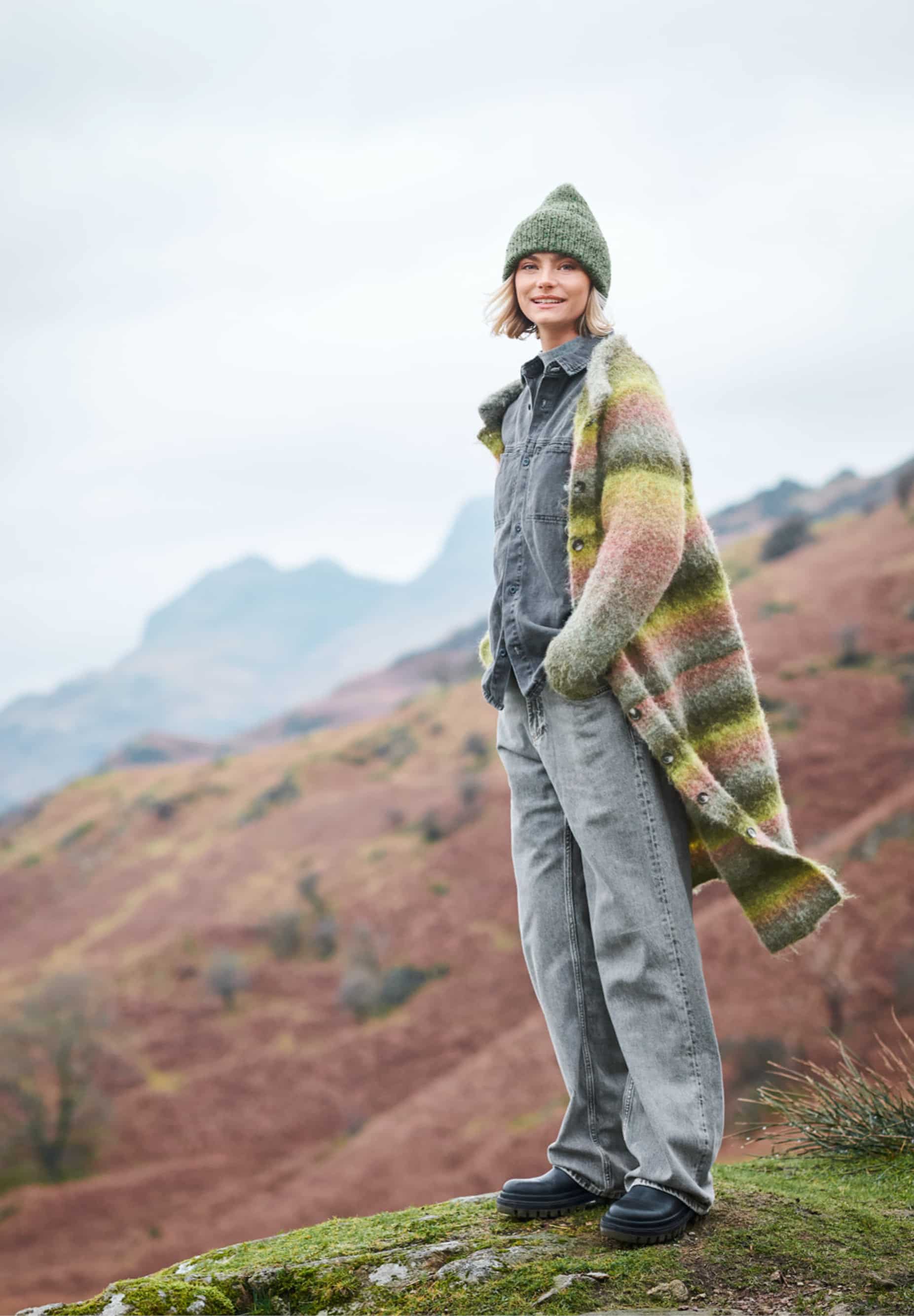 Frau trägt gestrickte, lange Jacke mit Farbeverläufen in Grün: Modell 21 aus Lovewool No. 23