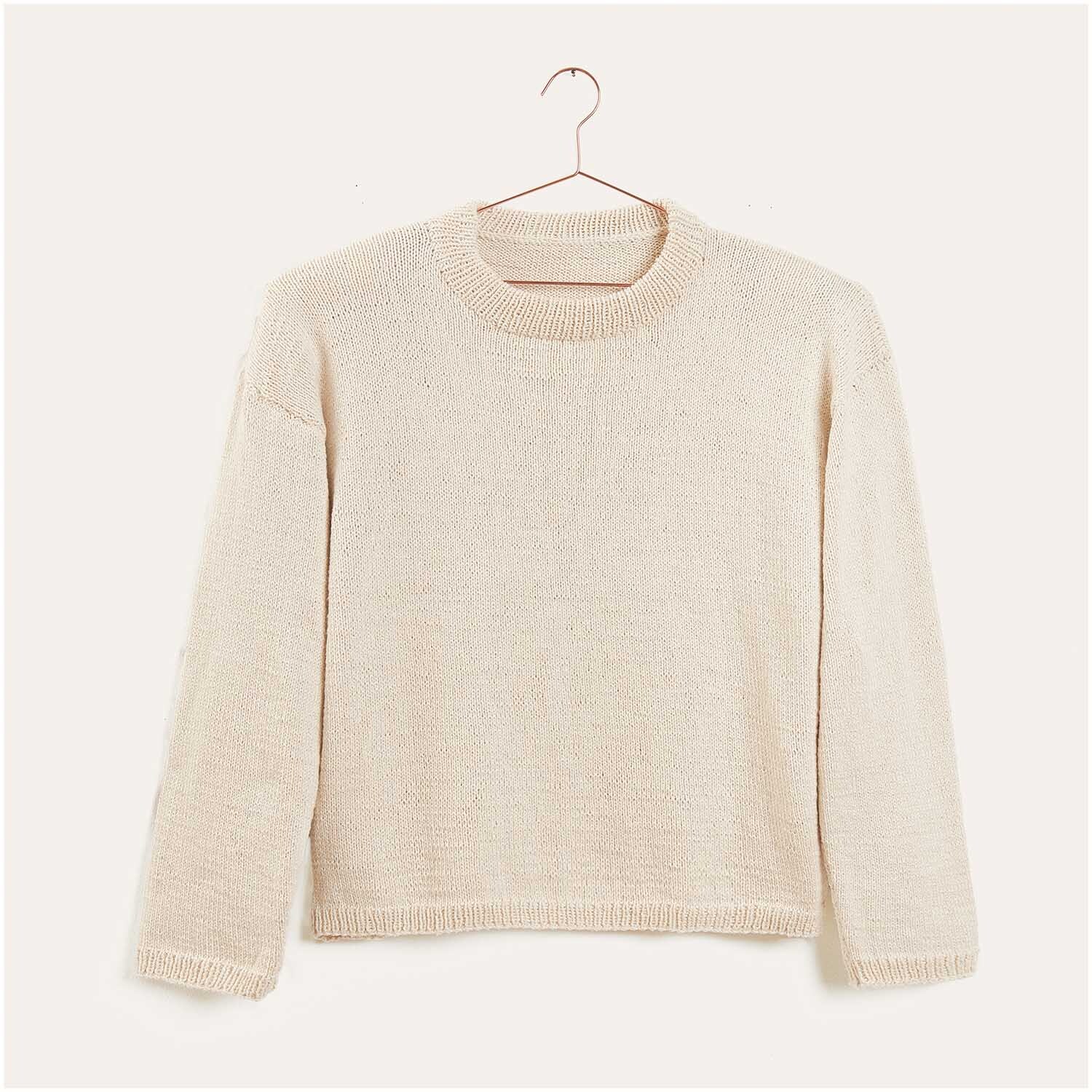 Strickset Pullover Modell 01 aus Luxury Knits von Rico Design Strickset Pullover Modell 01 aus Luxury Knits: Cremefarbener Pullover auf einem Kleiderbügel vor neutralem Hintergrund.