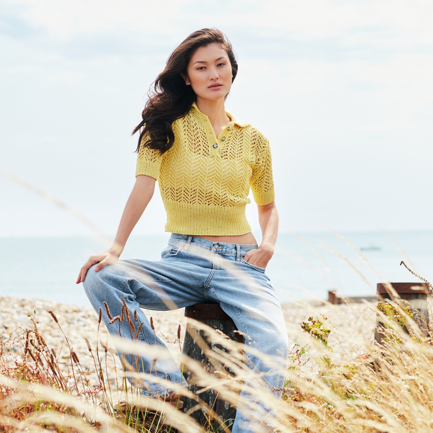 Strickset Poloshirt Modell 04 aus Lovewool No. 22 in Gelb, getragen von Frau am Strand.