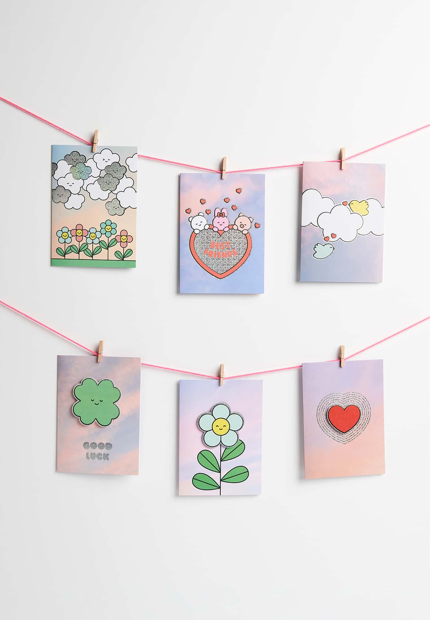 Karten mit Wolkenmotiven und illustrierten Figuren hängen dekorativ an Seile geklammert.