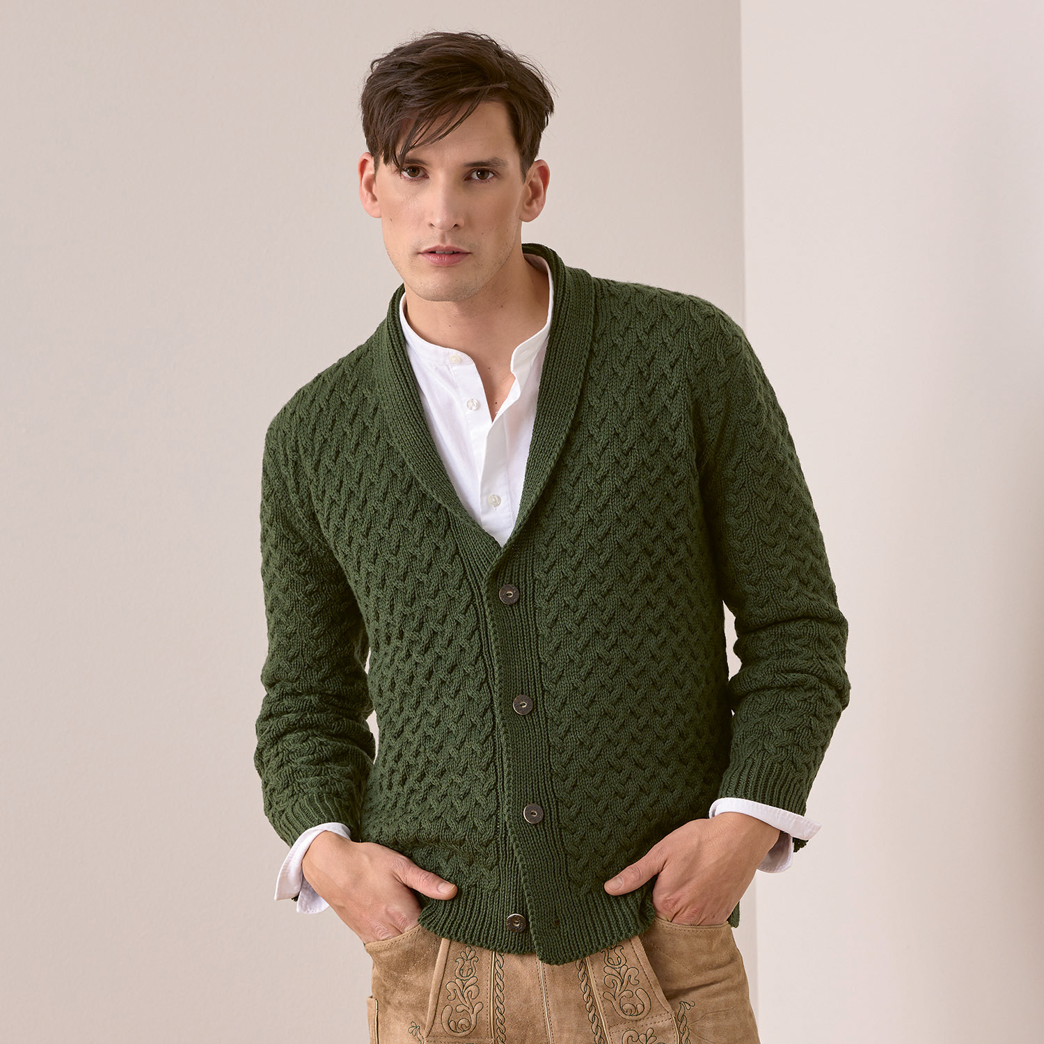 Trachtenjacke aus Essentials Merino Plus dk in Grün, getragen von einem Mann mit weißem Hemd und beiger Hose.