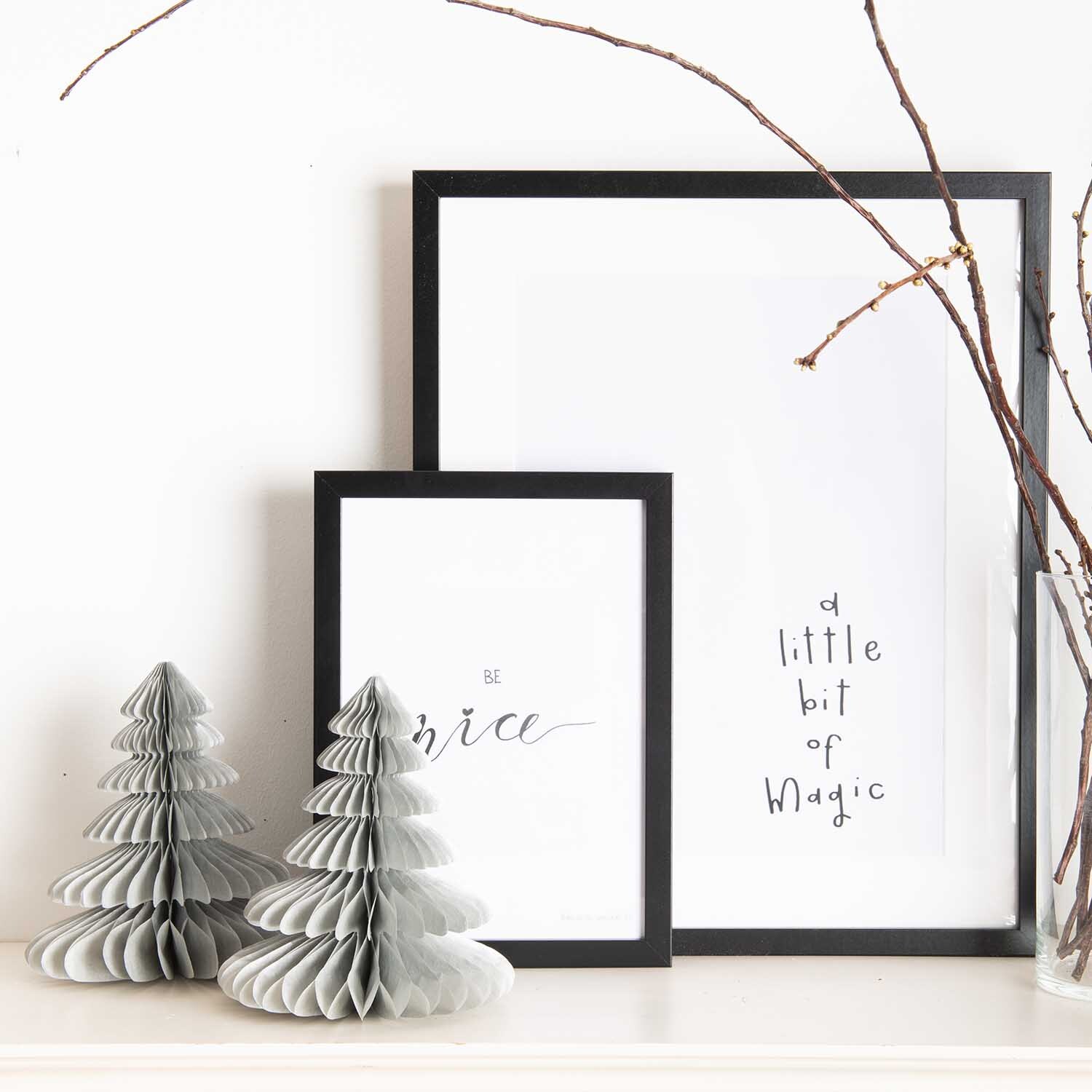 Wabenpapier Tannenbäume 20cm 2 Stück Farbe Silber von Rico Design Wabenpapier Tannenbäume 20cm 2 Stück in Silber neben zwei gerahmten Postern auf weißem Regal.