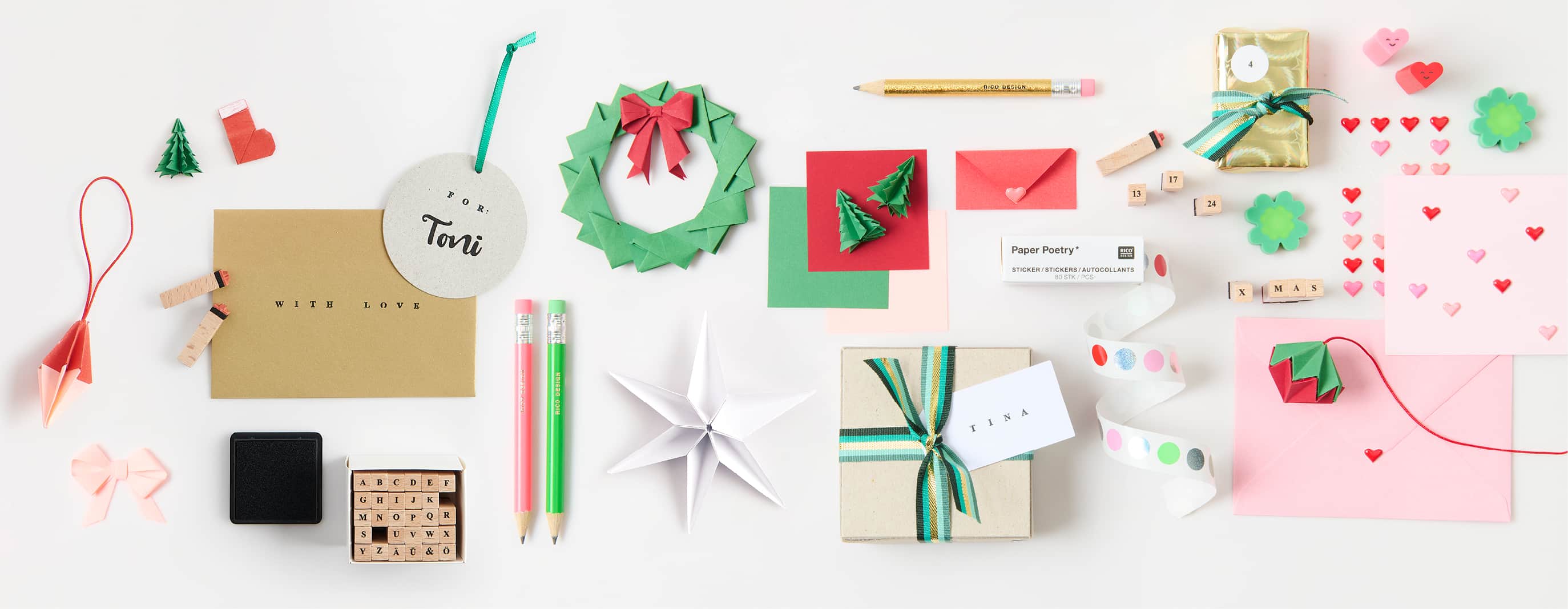 Papeterie-Artikel wie Origami-Papier, Stempel, und Sticker im Mini-Format liegen ausgebreitet auf weißem Hintergrund 