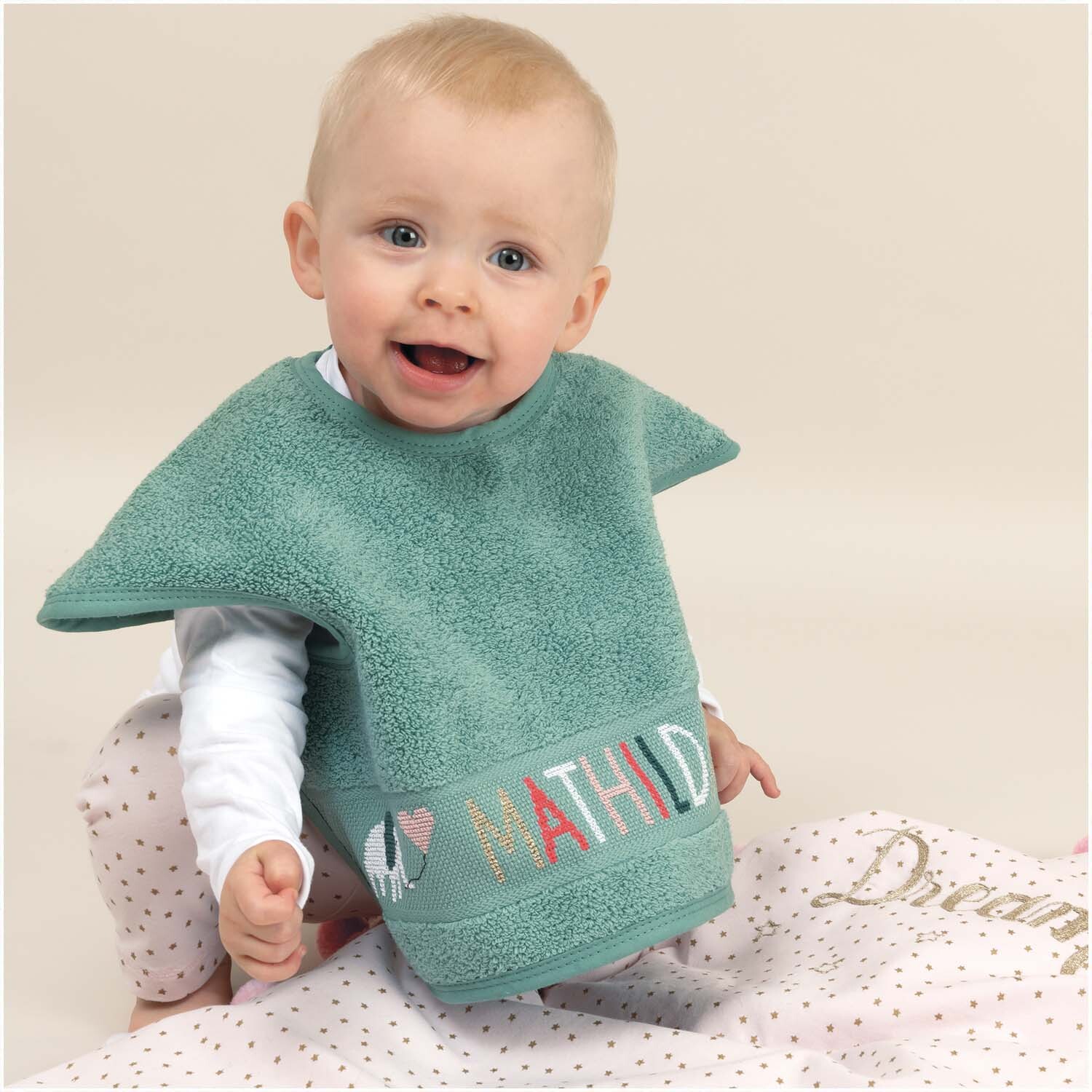 Ärmellätzchen 40x49cm Farbe Meergrün von Rico Design Ärmellätzchen 40x49cm in Meergrün von Rico Design, getragen von einem lächelnden Baby auf einer Decke.