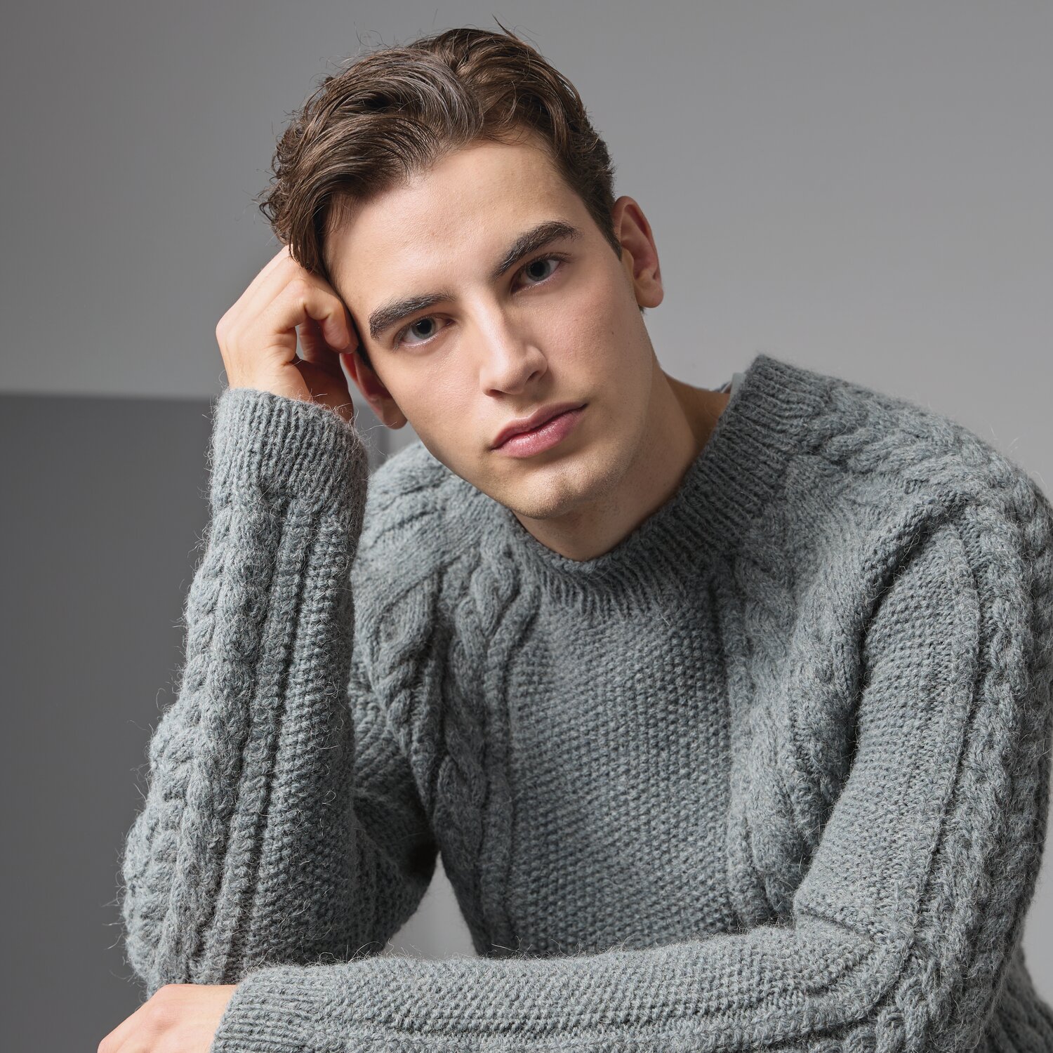 Strickset Pullover Modell 15 aus Made by Me Men No. 3 von Rico Design Strickset Pullover Modell 15 aus Made by Me Men No. 3: Mann trägt grauen Zopfmuster-Pullover.