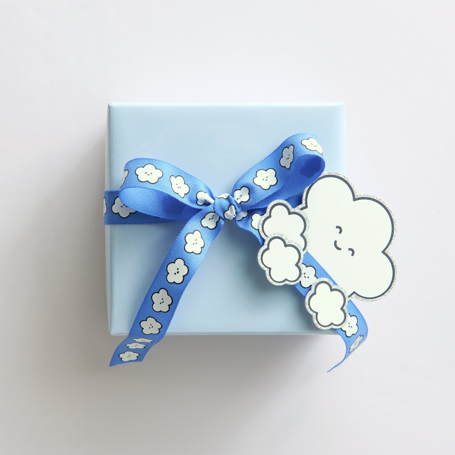 Paper Poetry Clip-Ons Chingu Wolken/Herzen Weiß: Geschenkbox mit blauem Band und Wolkenmotiv.