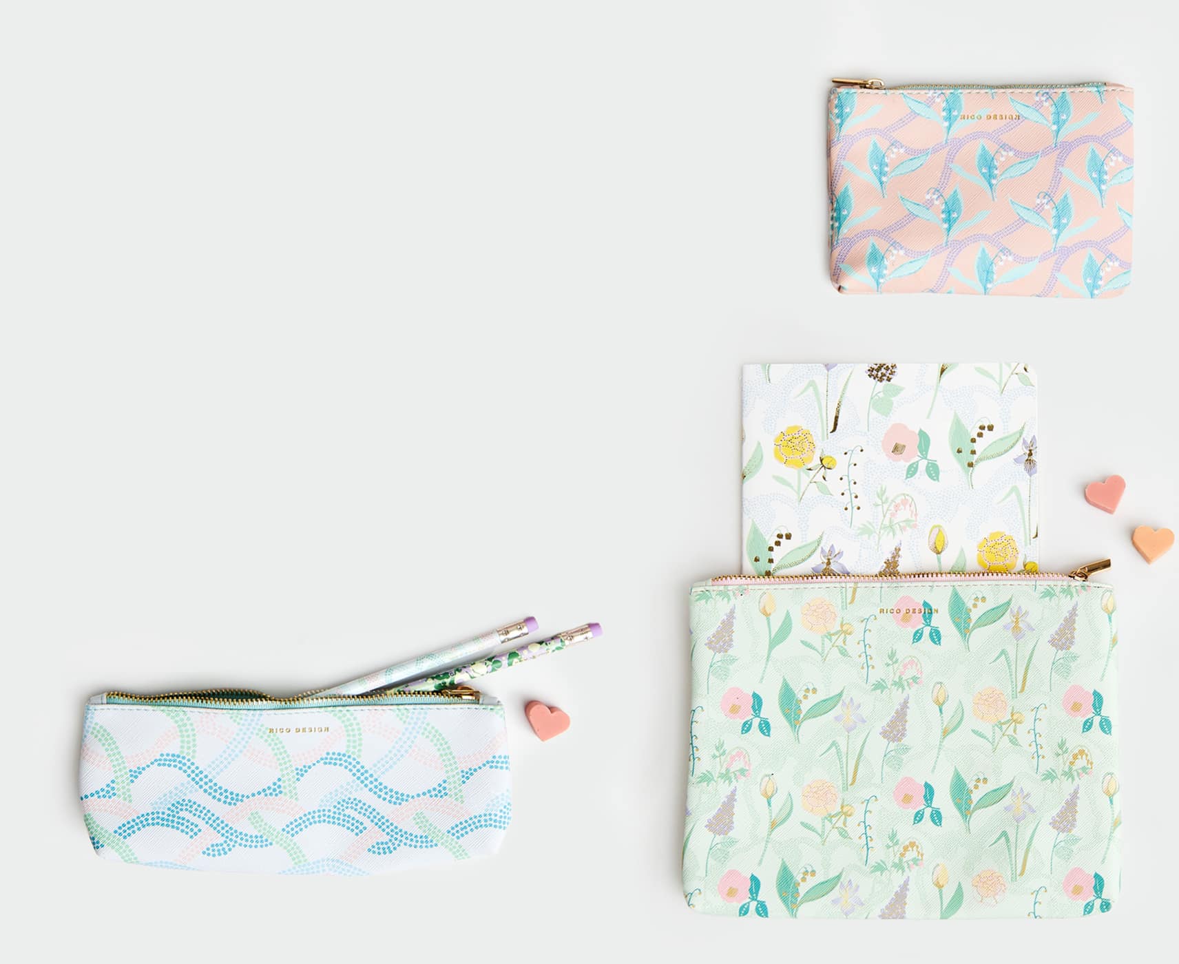 Pastellfarbene Etuis in verschiedenen Größen und floralen und abstrakten Mustern liegen auf grauem Hintergrund.