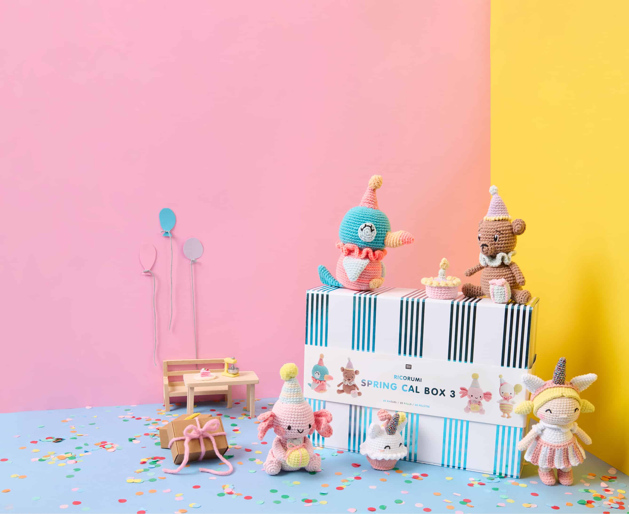 Ricorumi Spring CAL Box 3 ist vor bunten Wänden und umgeben von Häkelfiguren und Partyaccessoires dekoriert. 