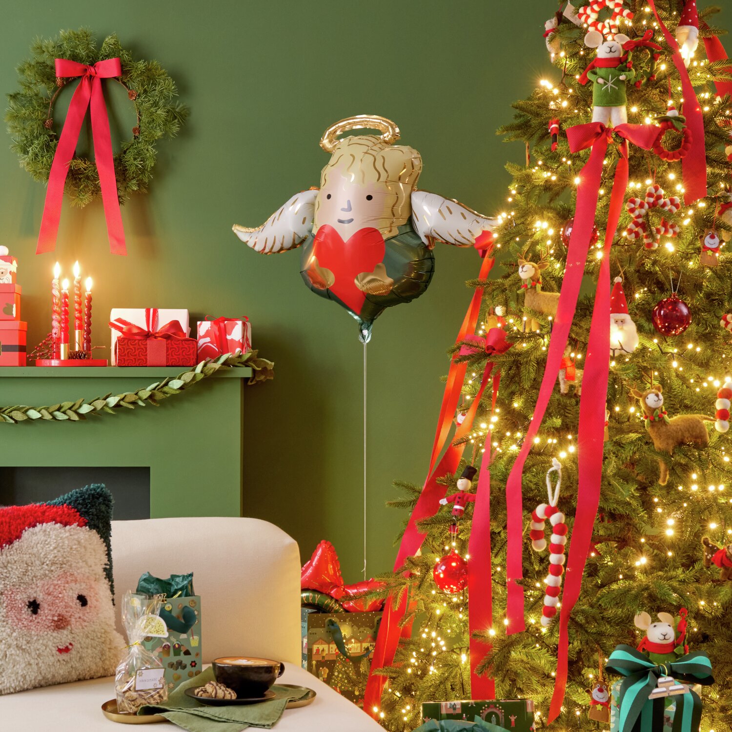Folienballon Engel mit Herz schwebt neben festlich geschmücktem Weihnachtsbaum in warmem Licht.