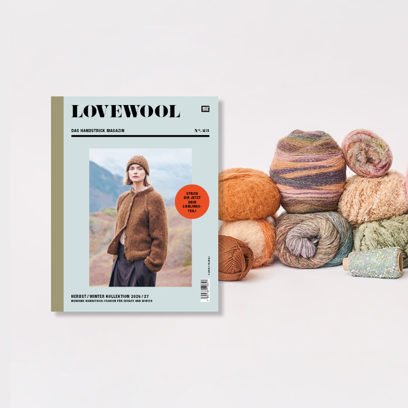 Strickheft Lovewool Nr. 23 neben einem Stapel Wollknäuel