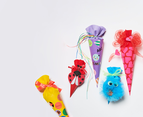Fünf gebastelte Schultüten in verschiedenen Farben und Designs, darunter Marienkäfer-, Frosch- und Krümelmonsterfigur