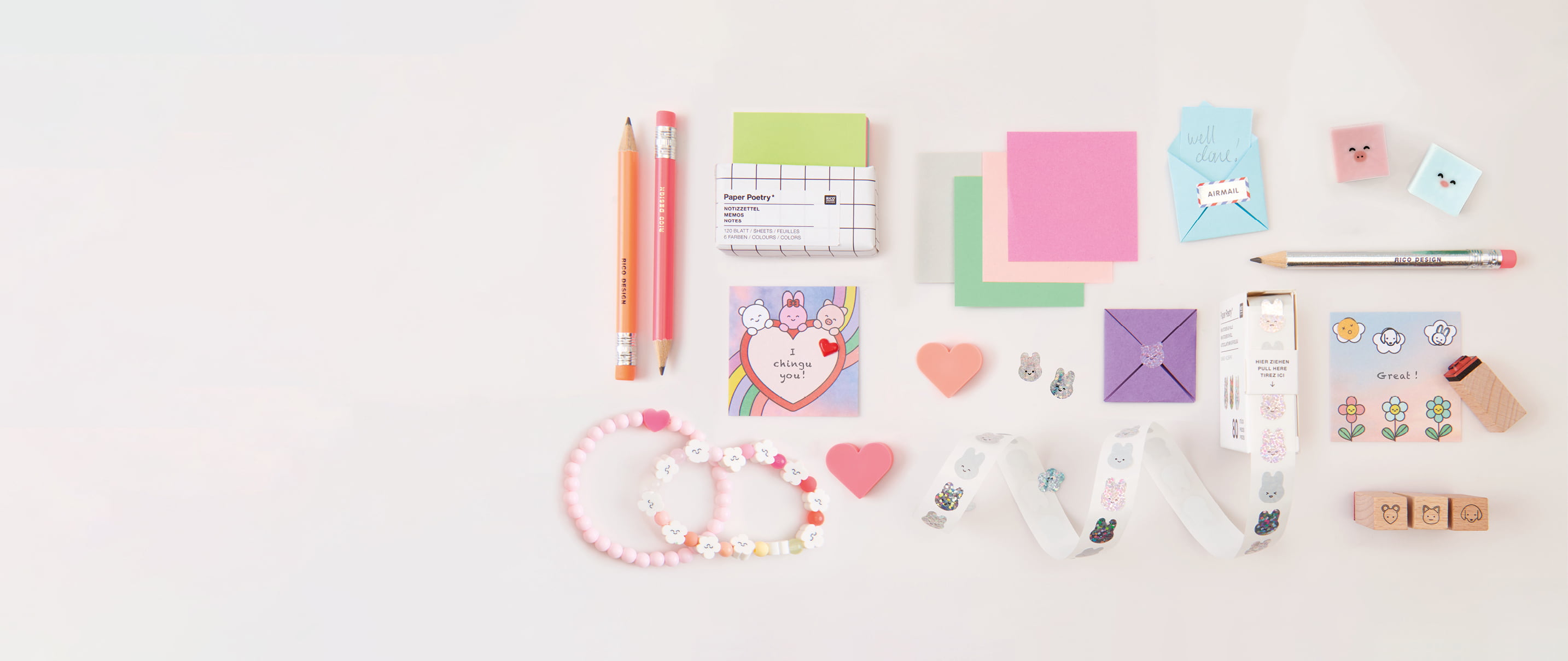Papeterie-Artikel wie Origami-Papier, Stempel und Sticker im Mini-Format liegen ausgebreitet auf grauem Hintergrund.  