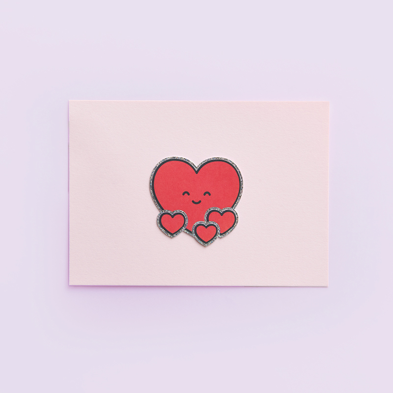 Rote Clip-Ons Herz mit lächelndem Gesicht auf einer Karte