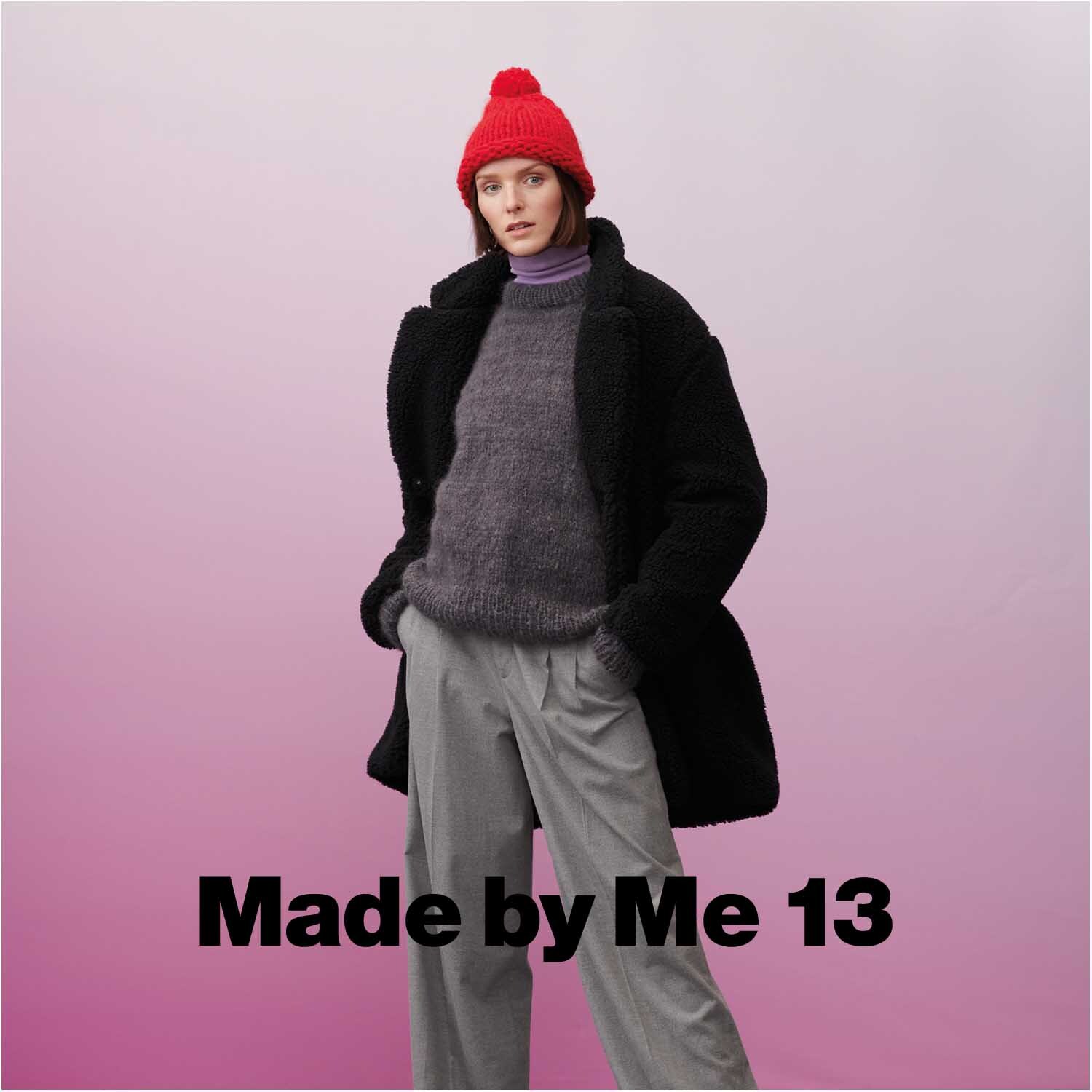 Fashion Alpaca Cozy Up! Frau in schwarzem Mantel und roter Mütze von Rico Design vor rosa Hintergrund.