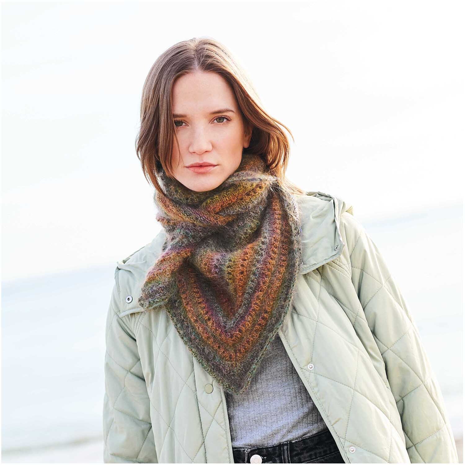 Fashion Mohair Rainbows: Frau trägt gestricktes Tuch in Regenbogenfarben von Rico Design am Strand.