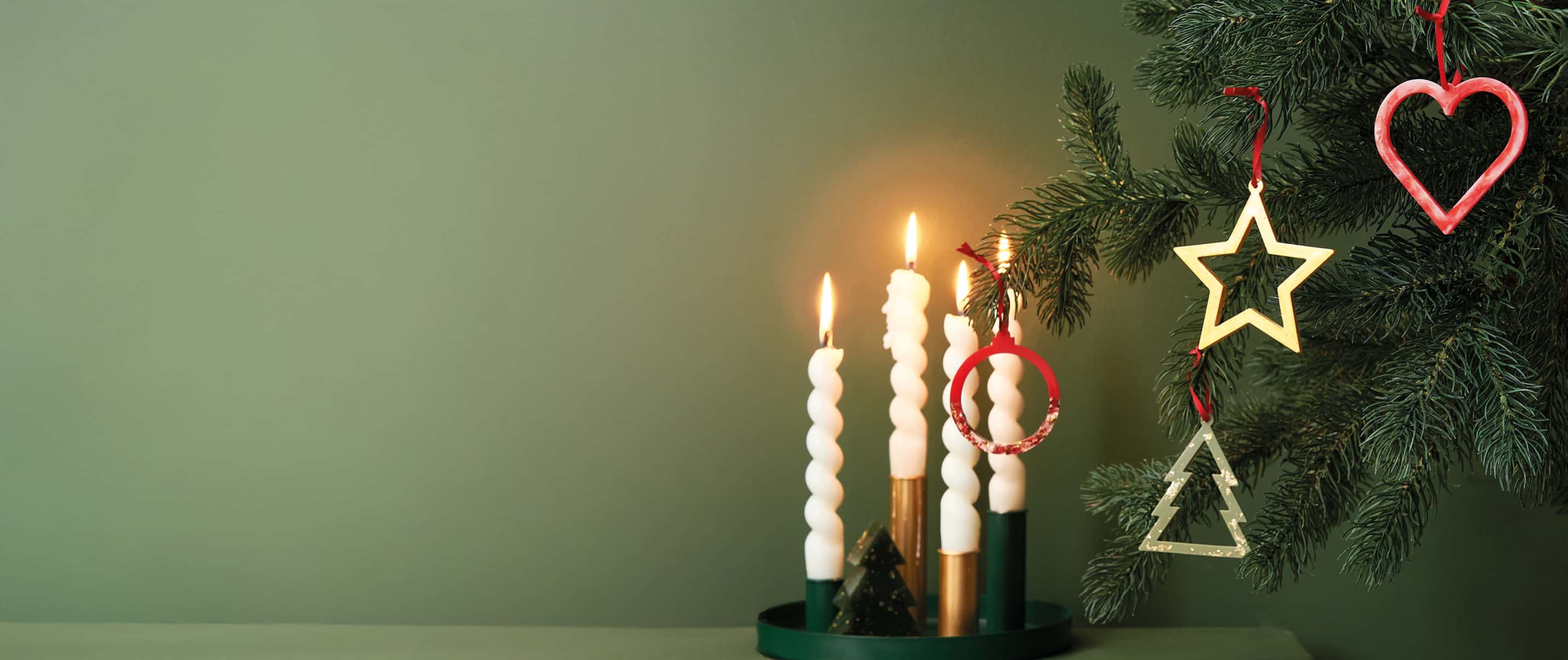 Weihnachtsanhänger aus Resin hängen weihnachtlich dekoriert an einem Tannenzweig. 