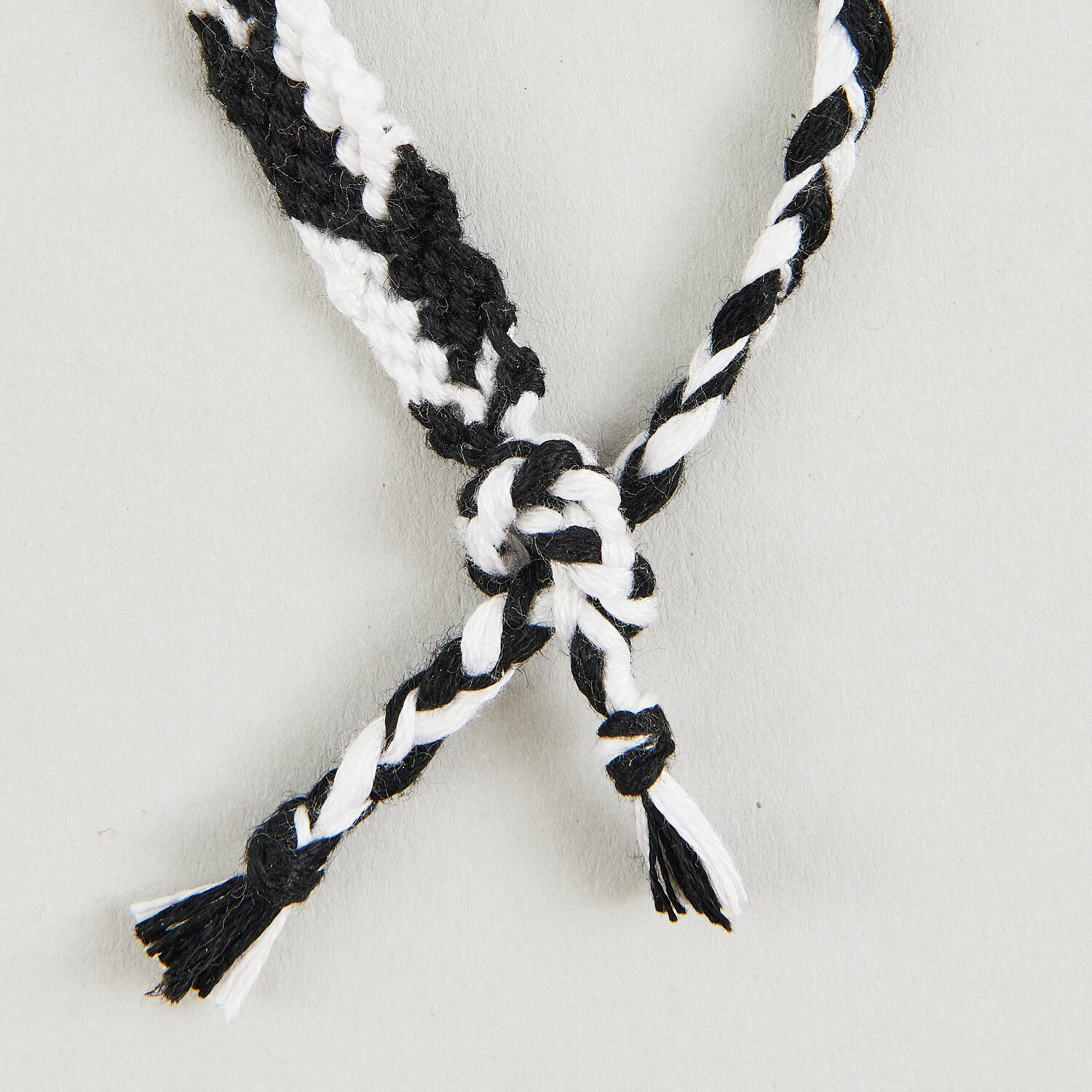 DIY Freundschaftsarmbänder Set Classic Colours zeigt ein schwarz-weiß geflochtenes Armband.