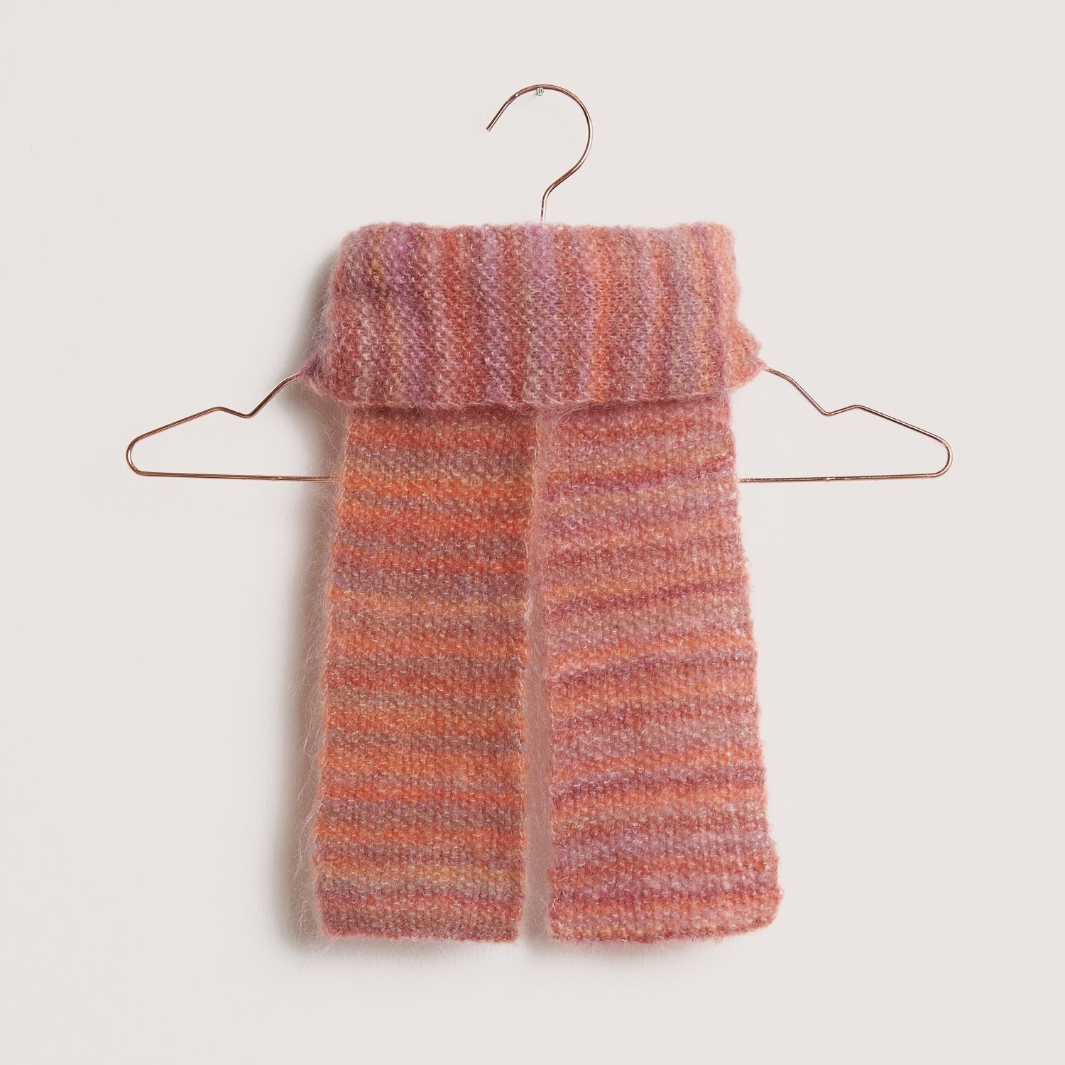 Fashion Meri Mohair Print Schal in Rosa-Orange auf einem Kleiderbügel, ideal für kühle Tage.