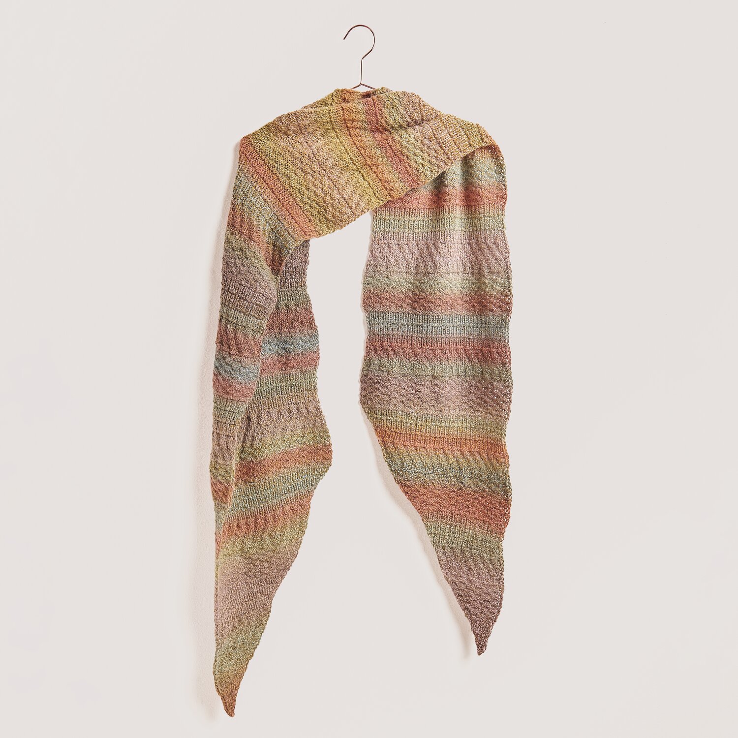 Creative Melange Alpaca Wonderball dk Schal in sanften Pastelltönen, aufgehängt an einem Haken. Ideal für Herbstmode.