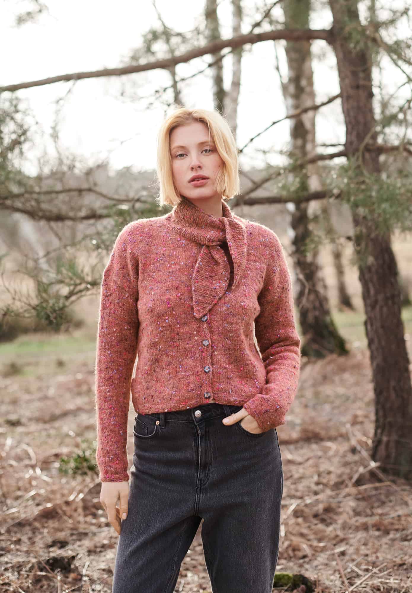 Frau trägt gestrickte Jacke mit Tuchdetail und Knopfleiste in Rosatönen: Modell 31 aus Lovewool No. 21