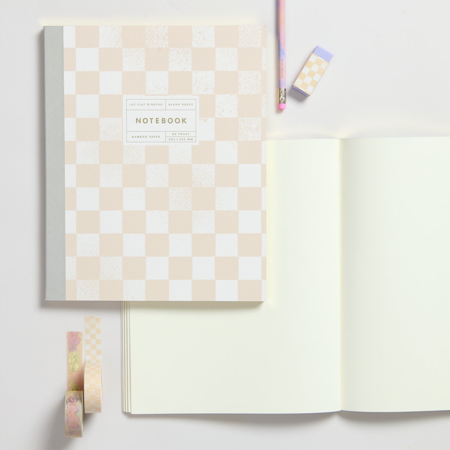 Notizbuch Sky L Schachbrettmuster mit 80 Blatt, cremefarbenes Design, 100g/m² Papier, neben offenem Notizbuch und buntem Stift.